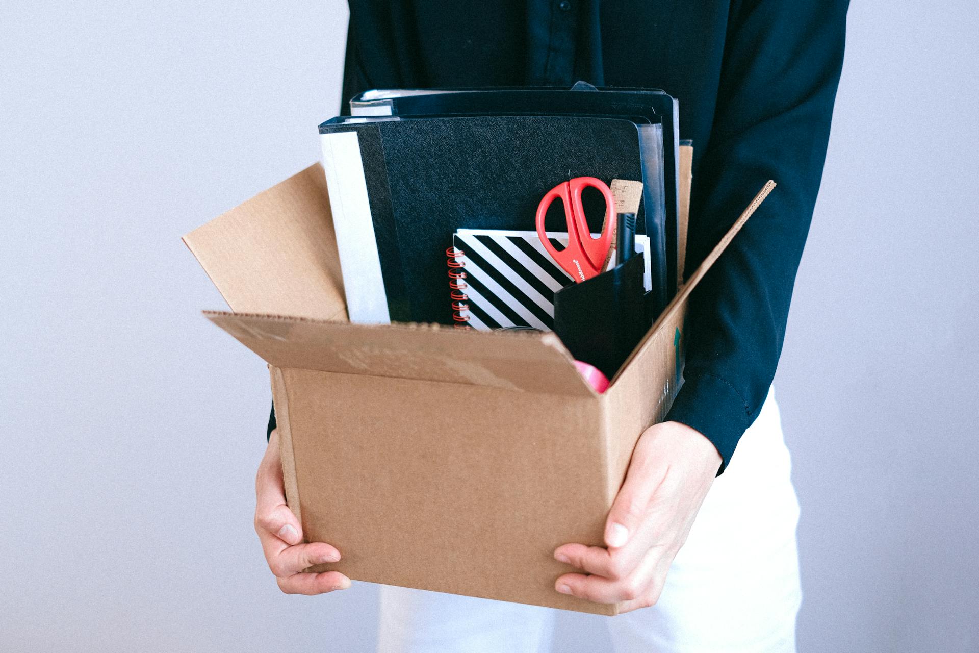 A woman holding a carton with her office items inside | Source: Pexels