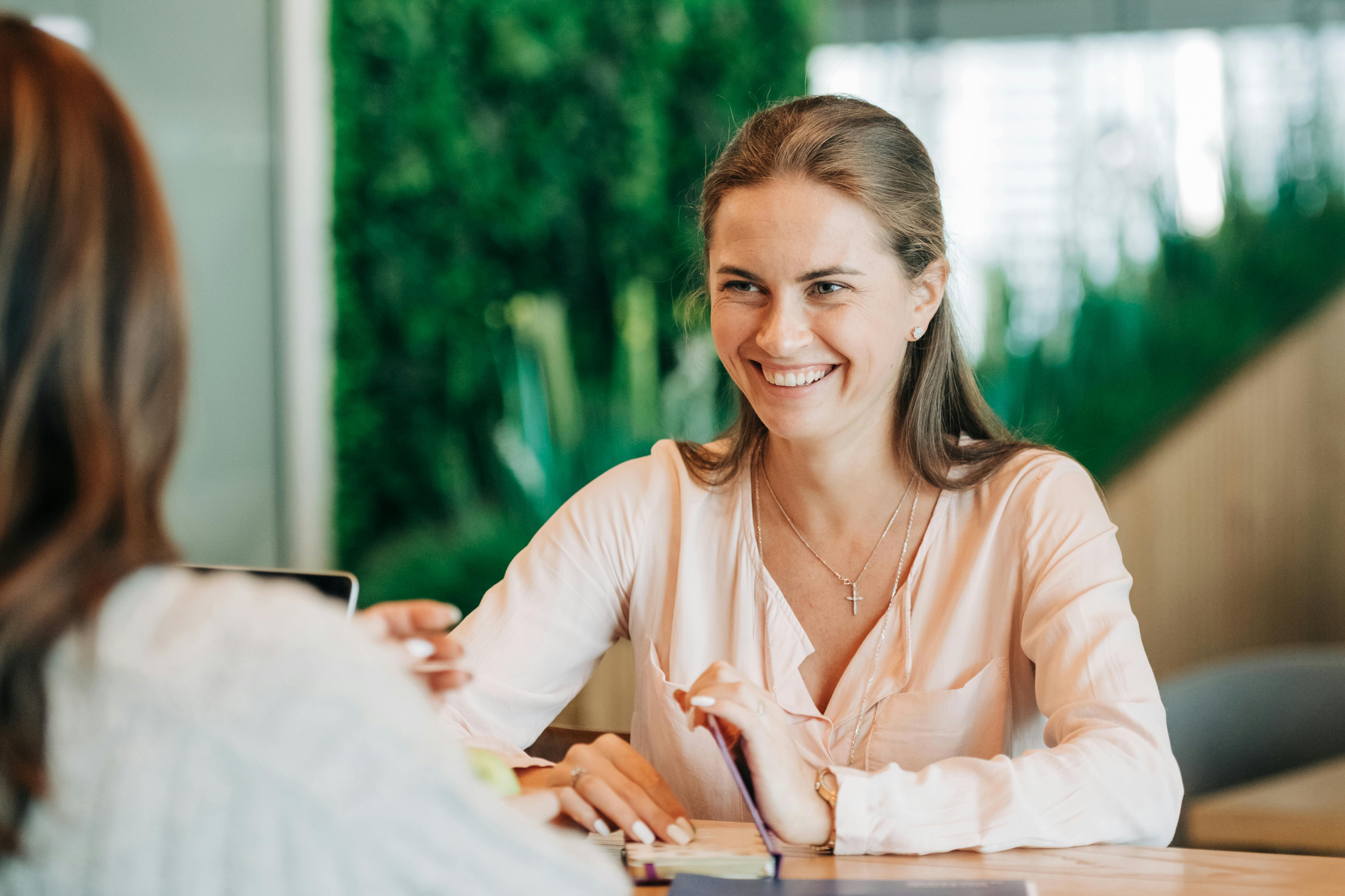 A smiling woman chatting with her colleague | Source: Pexels