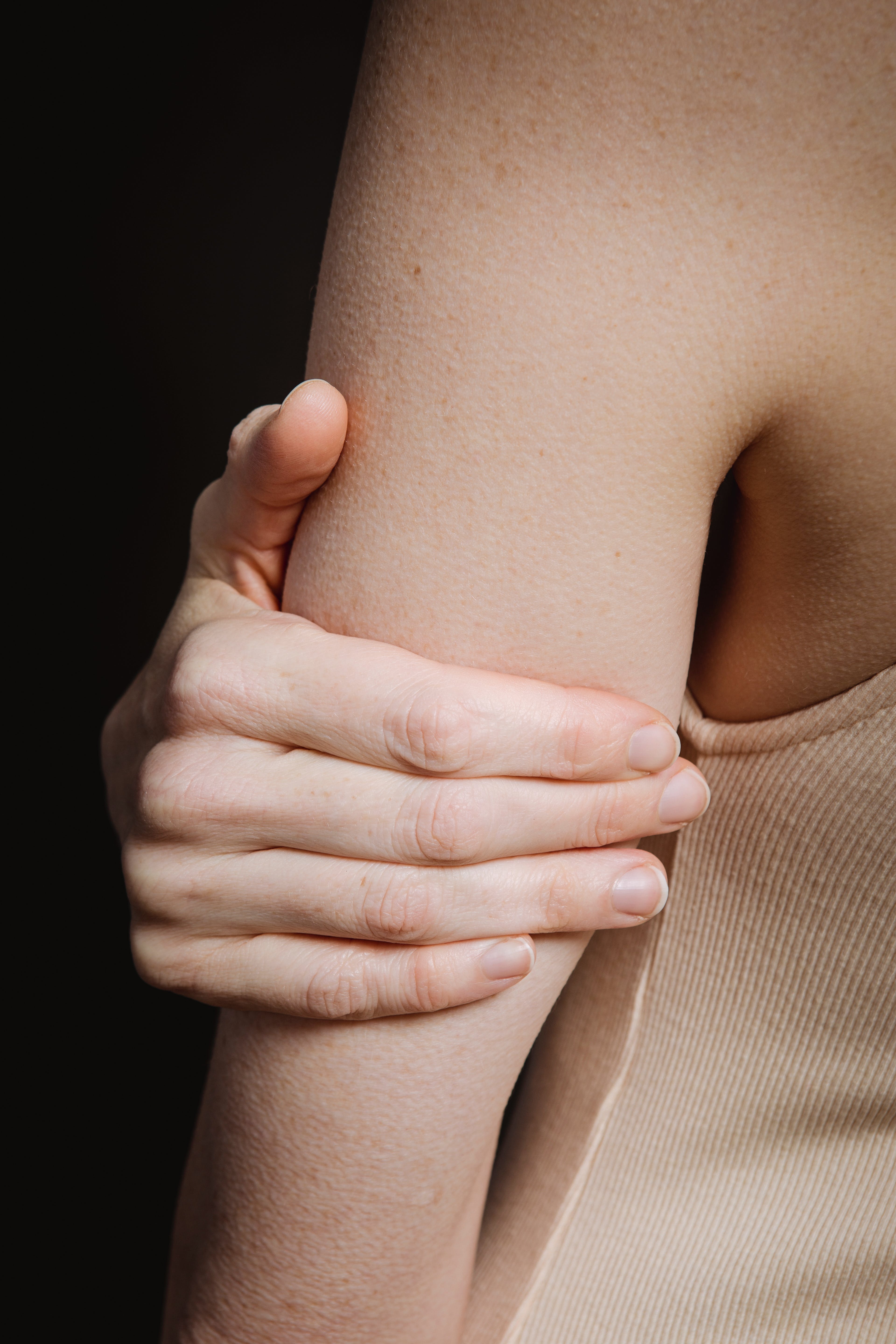 A person holding their arm. | Source: Pexels