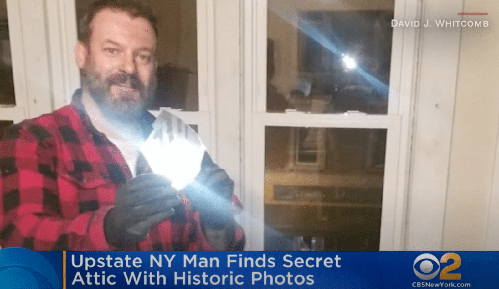 A man who discovered hidden treasures in his attic holds up a glass negative | Photo: Youtube/CBS New York