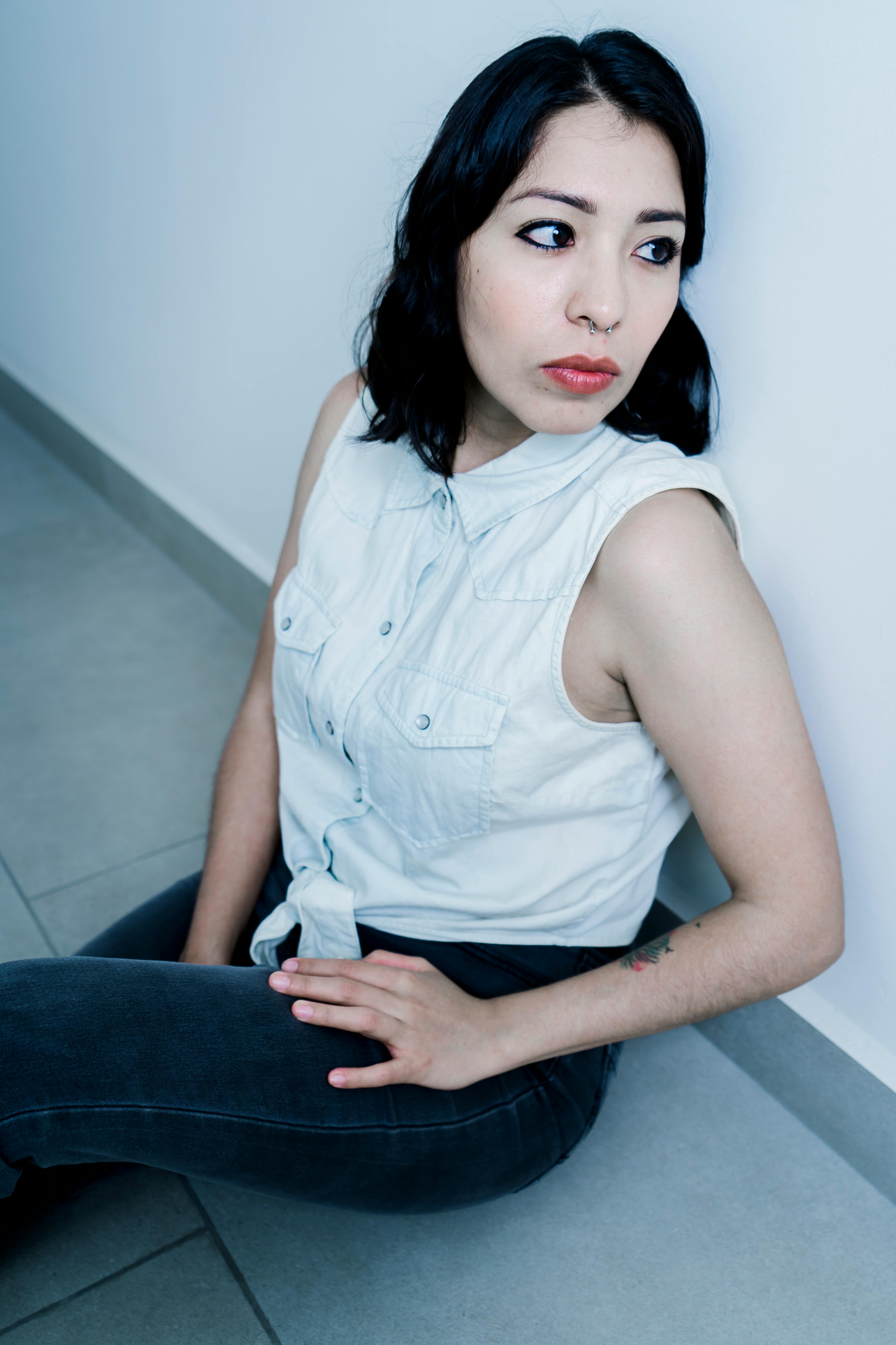 A serious woman looking to the side while sitting on the floor | Source: Pexels