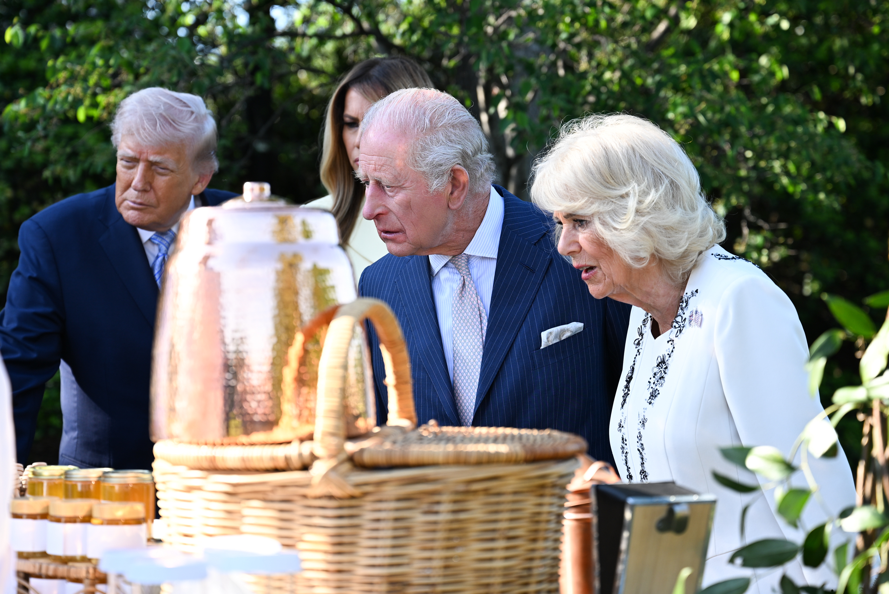King Charles III and Queen Camilla were later seen leaning in to examine a display of refreshments during the outdoor reception, as President Donald Trump and First Lady Melania Trump looked on nearby. The candid moment, framed by wicker baskets and glass jars, offered a glimpse into the more informal side of the gathering, as the royal couple engaged with elements of the event beyond the formal greetings.