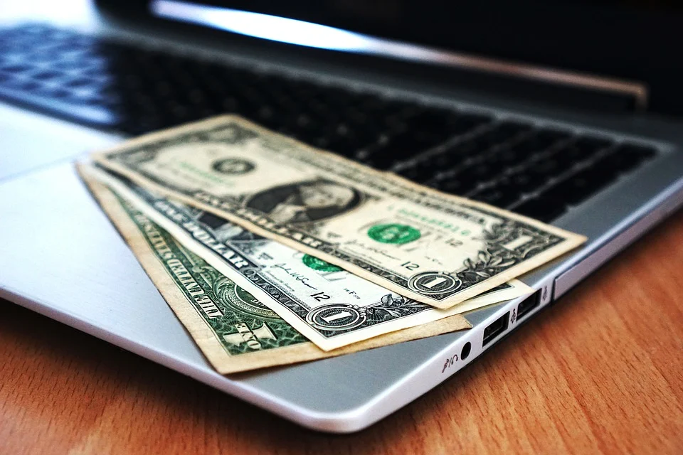 Tres billetes de dólar sobre el teclado de una computadora portátil. | Foto: Pixabay
