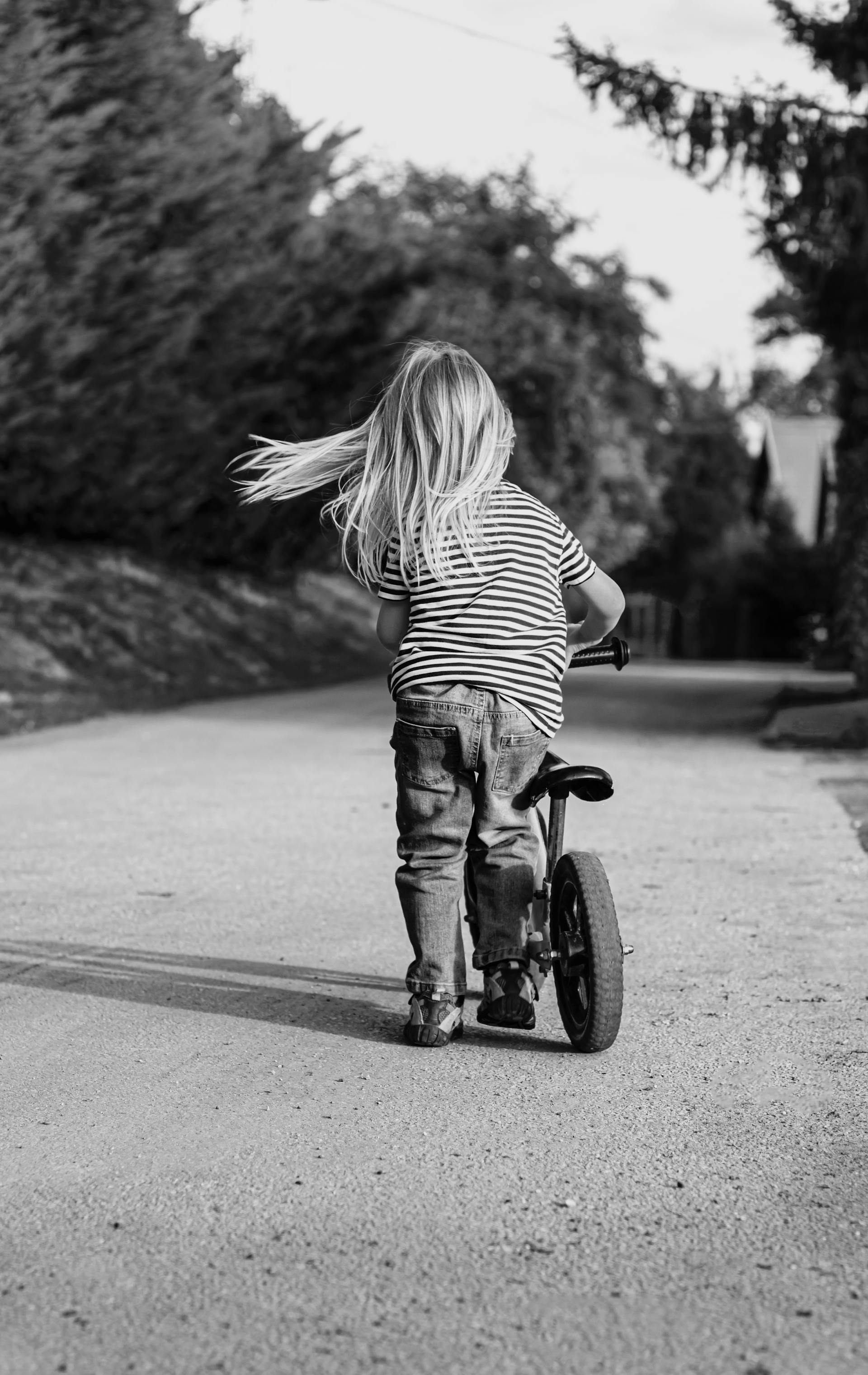 Grayscale shot of a little girl riding her bicycle | Source: Pexels