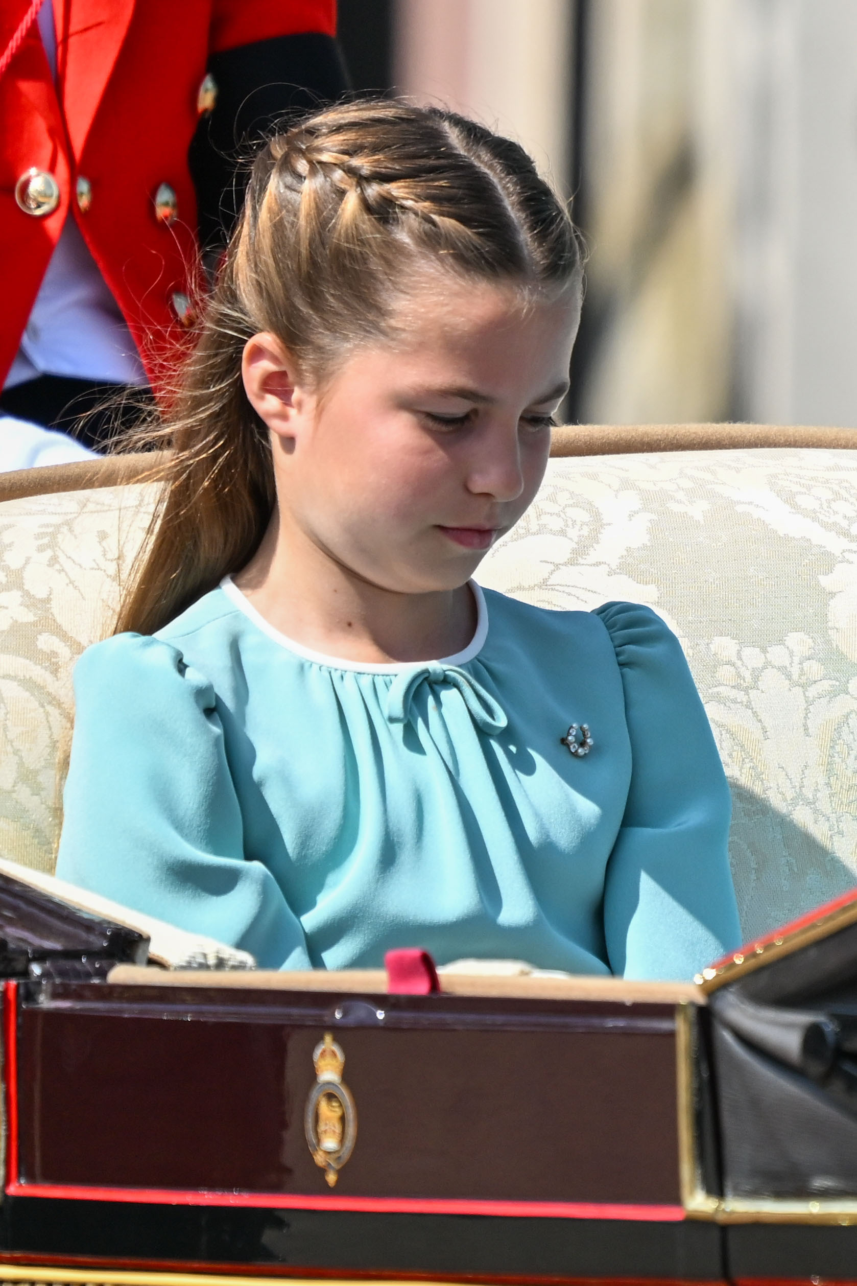 Princess Charlotte of Wales is photographed in her white and aquamarine dress on her way to Buckingham Palace during Trooping The Colour 2025 in London, England on June 14, 2025. She wears a beautiful smile and sets the internet abuzz with her long, thick brown hair, worn loose with a neat center part.