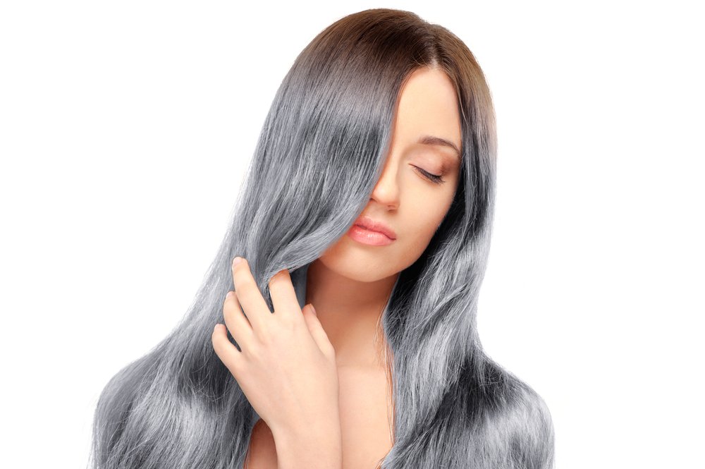 Retrato de mujer con los ojos cerrados con la mano sobre su largo cabello gris. | Foto: Shutterstock
