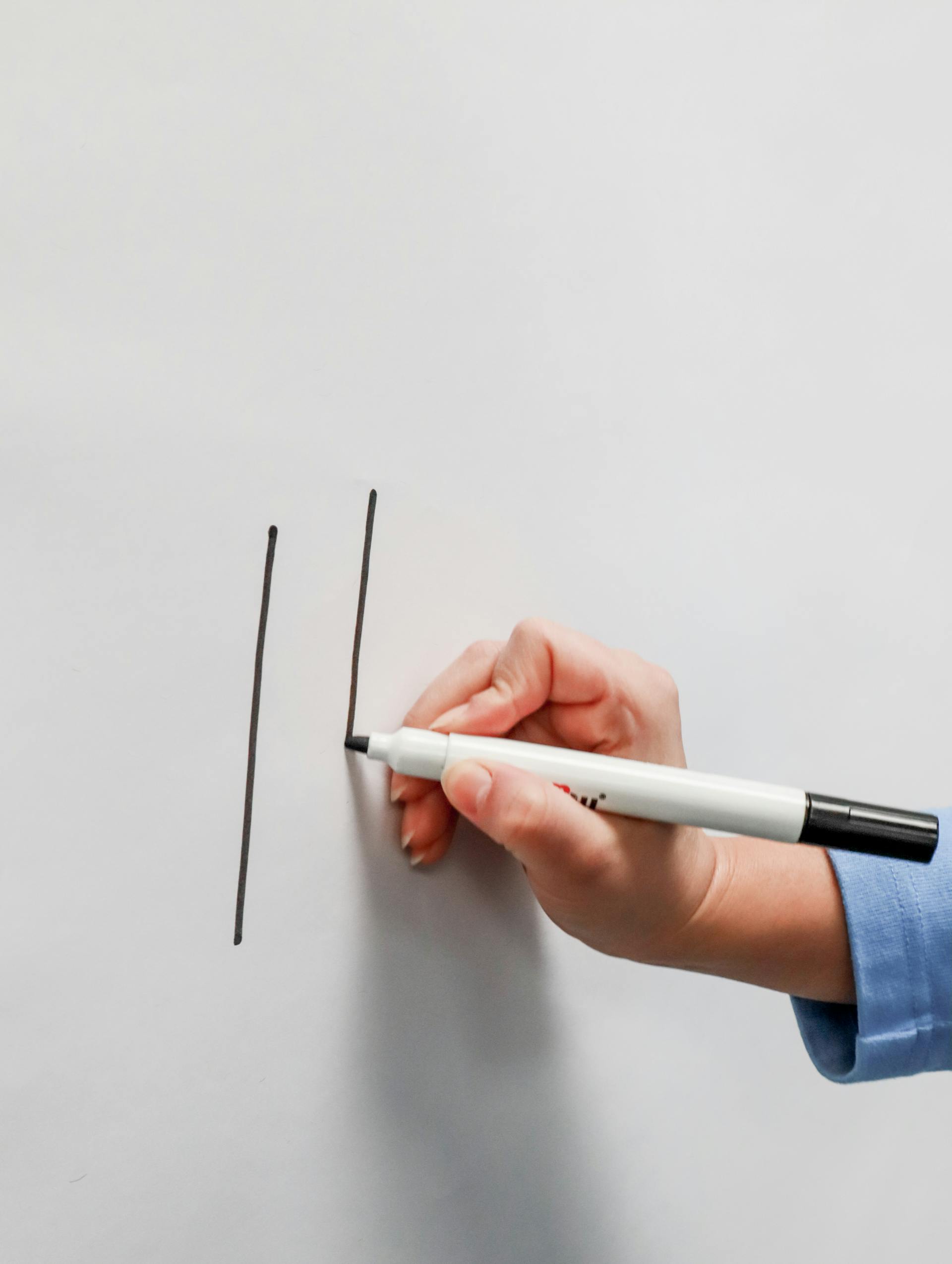 A closeup of a person writing on a whiteboard | Source: Pexels