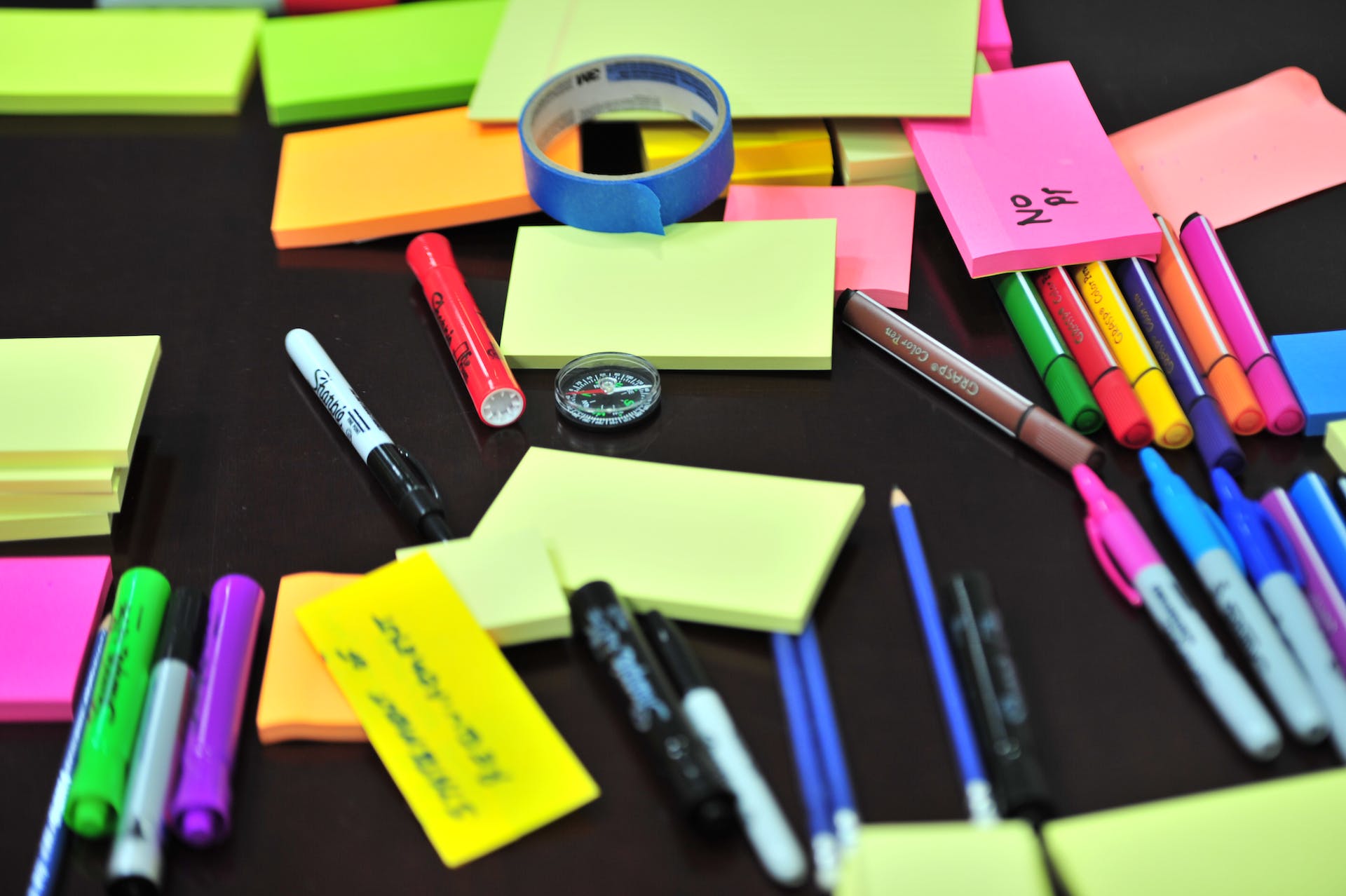 Sticky notes and pens scattered on a desk | Source: Pexels