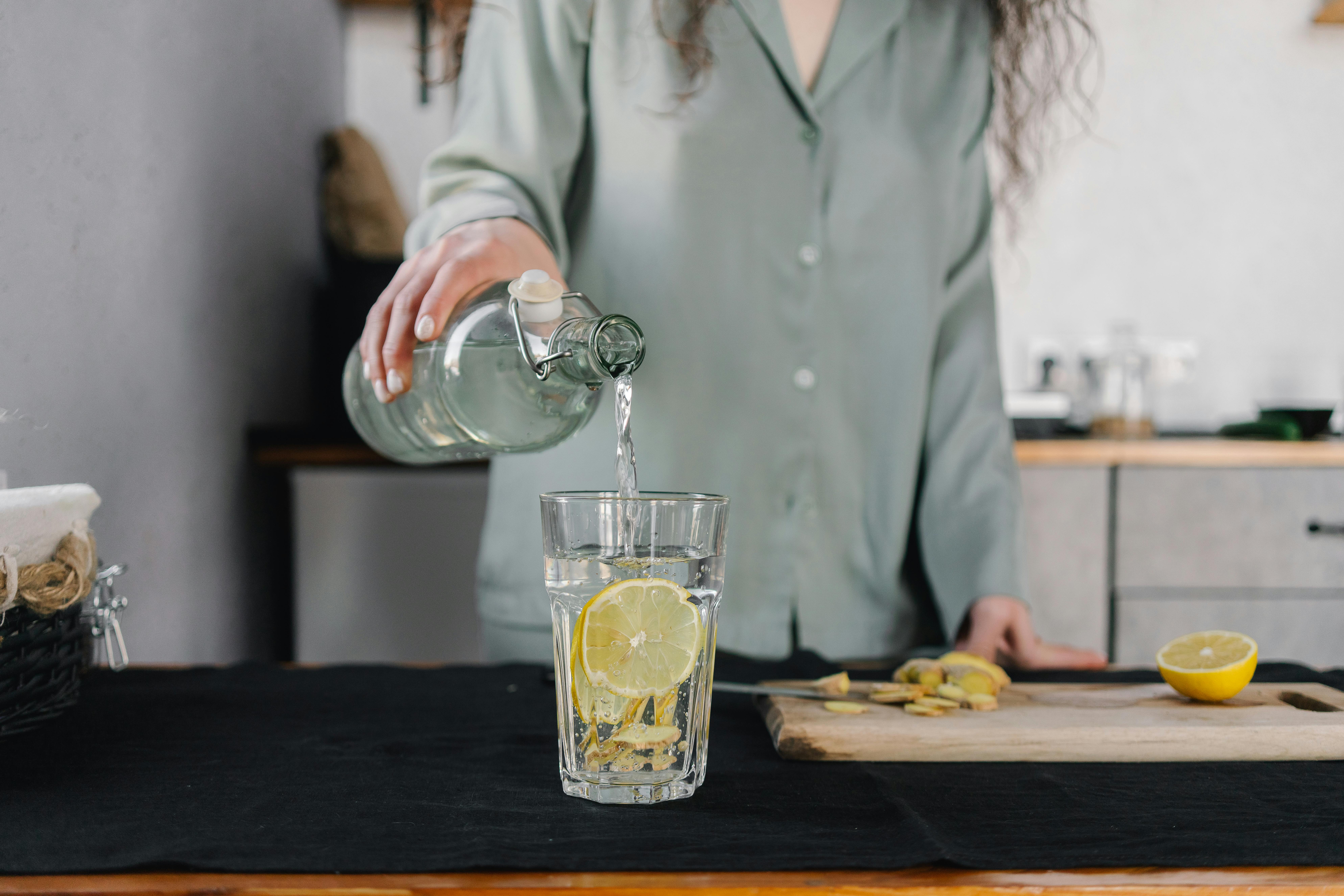 A woman preparing a glass of lemon water | Source: Pexels