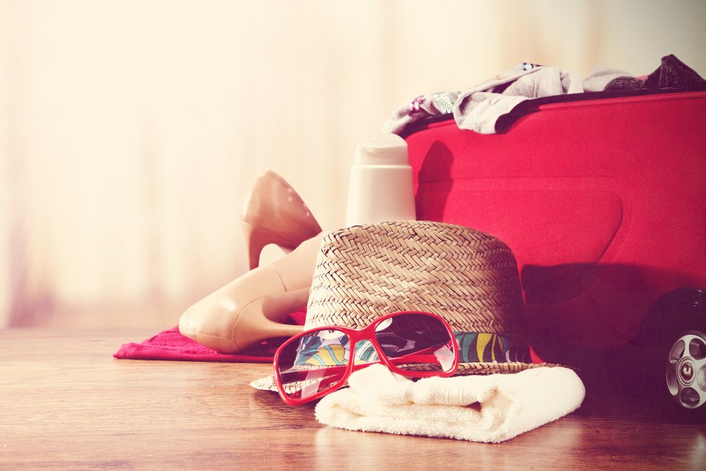Maleta roja abierta con gorro y gafas de sol. Fuente: Shutterstock Maleta roja abierta con gorro y gafas de sol. Fuente: Shutterstock