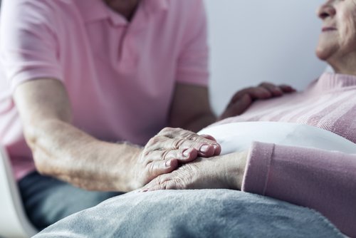 Senior man holding hand of his ill wife. | Source: Shutterstock.