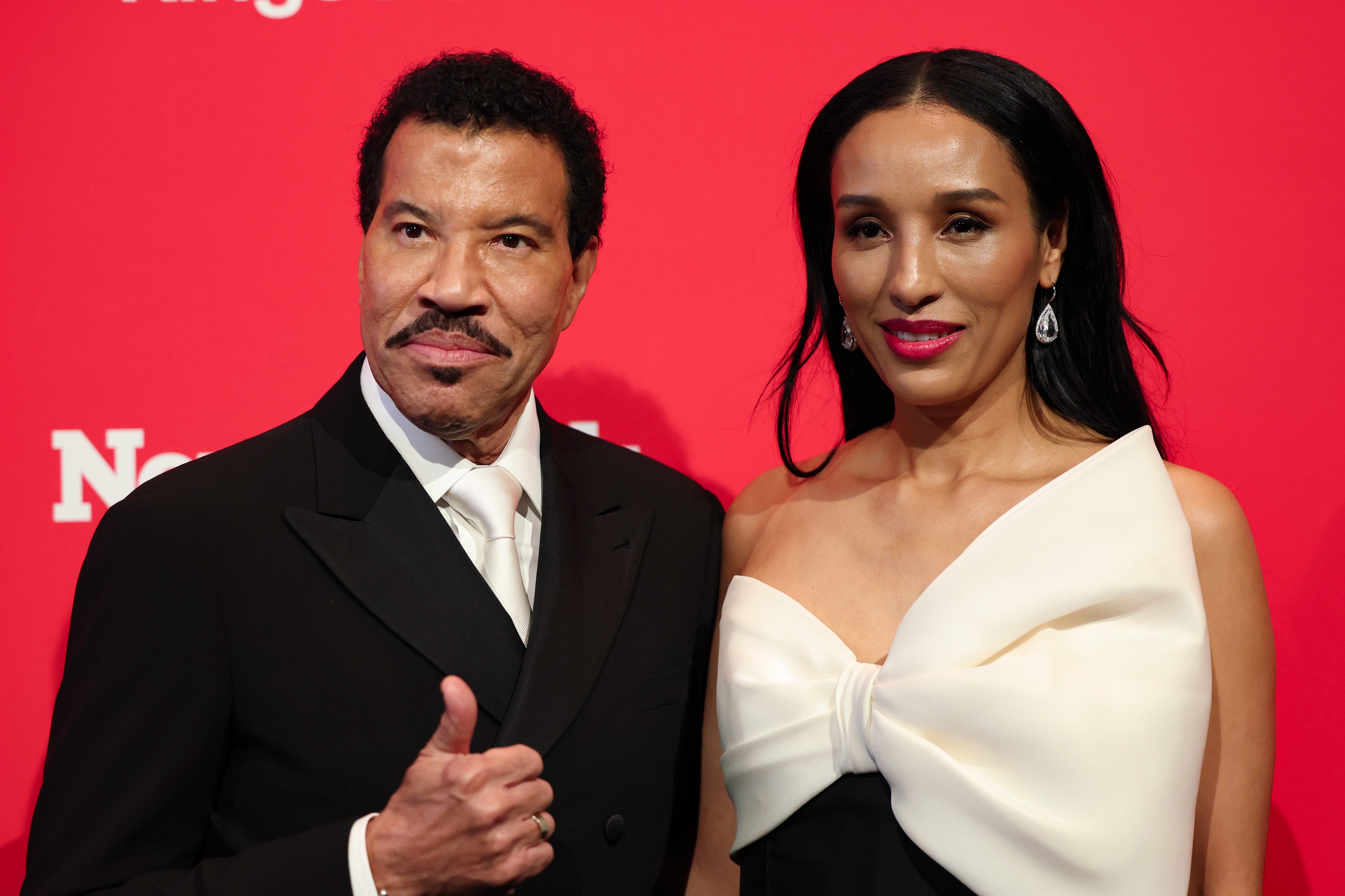 Richie gives a cheerful thumbs up as he stands beside Parigi, both dressed to impress and radiating confidence. Lisa's elegant gown complements Richie's classic suit, making them look every bit the glamorous power couple of the night.
