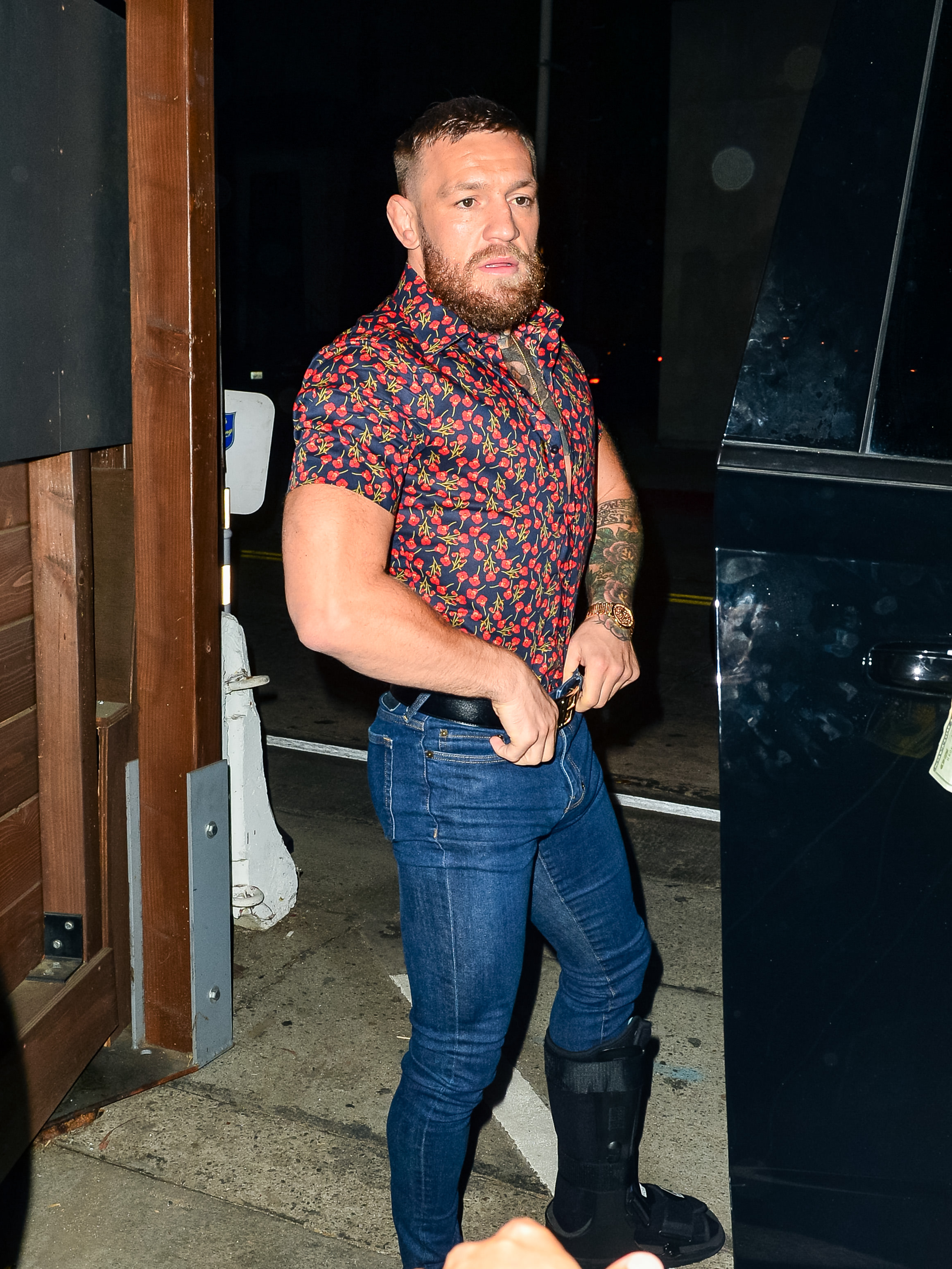 Conor McGregor is seen in Los Angeles on August 5, 2021, less than a month after suffering a broken leg during UFC 264. Although wearing a protective walking boot as he continued his recovery, the former UFC champion's noticeably broader arms and upper body hinted at the dramatic muscle gain that would become even more apparent in the months that followed.
