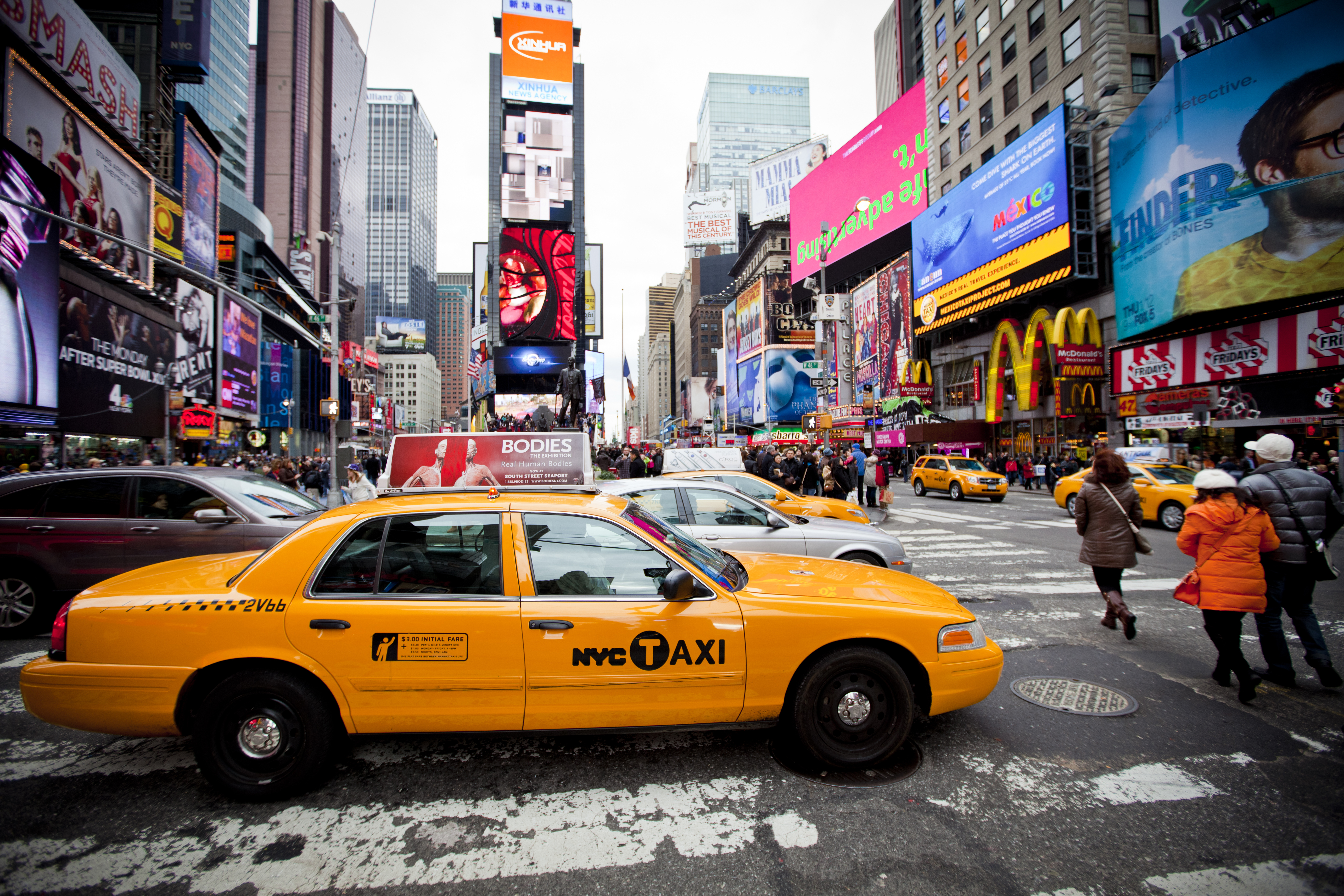 Yellow cab speeds through Times Square the busy tourist intersection of neon art | Source: Shutterstock.com