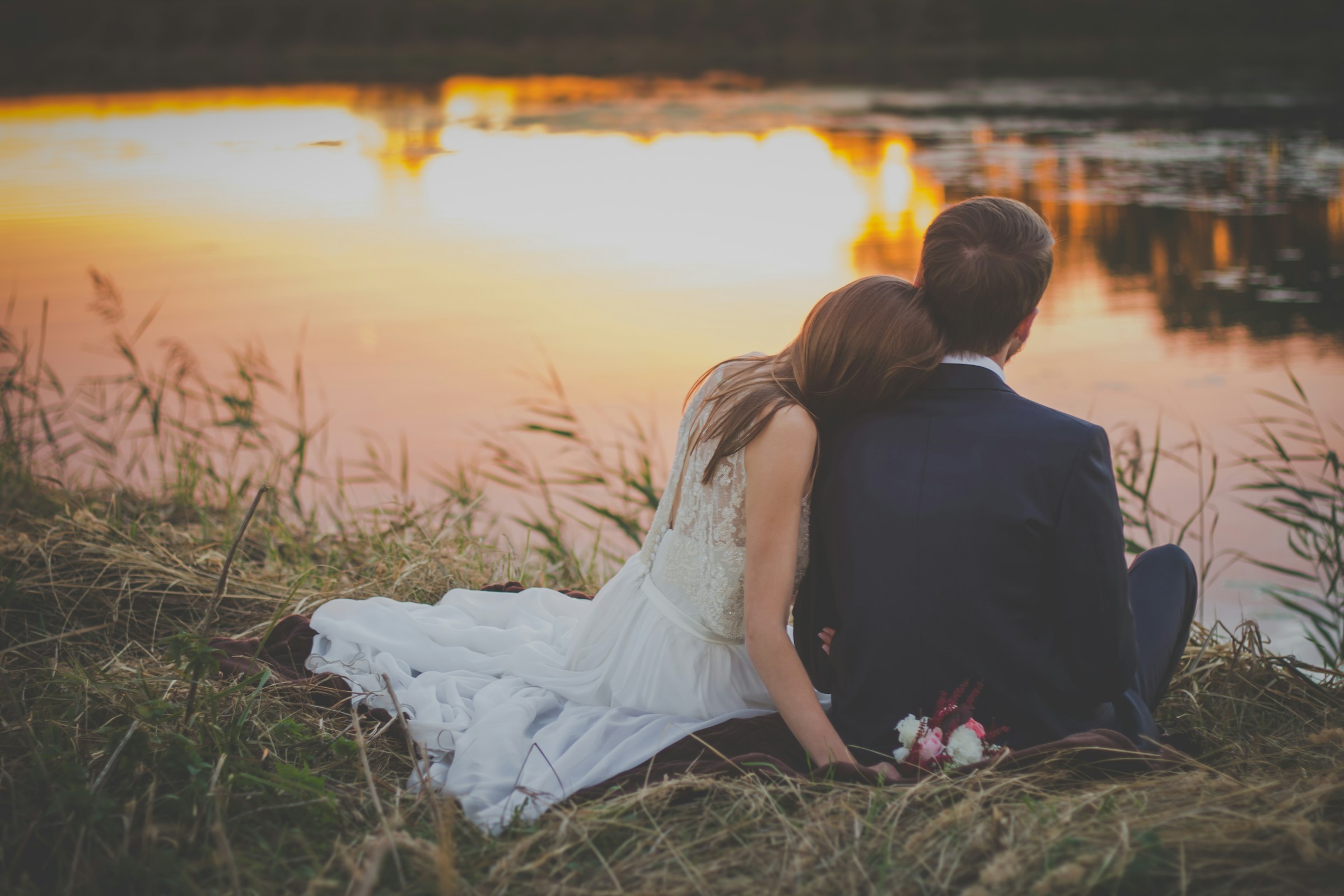 A bride and groom sitting by a lake | Source: Unsplash