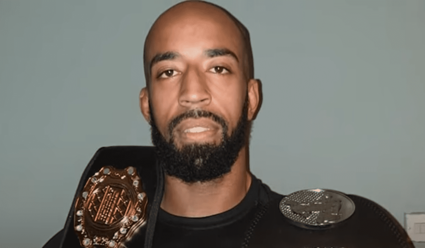 Champion MMA fighter Jahreau Shepherd holding two title belts | Photo: YouTube/EveningStandard