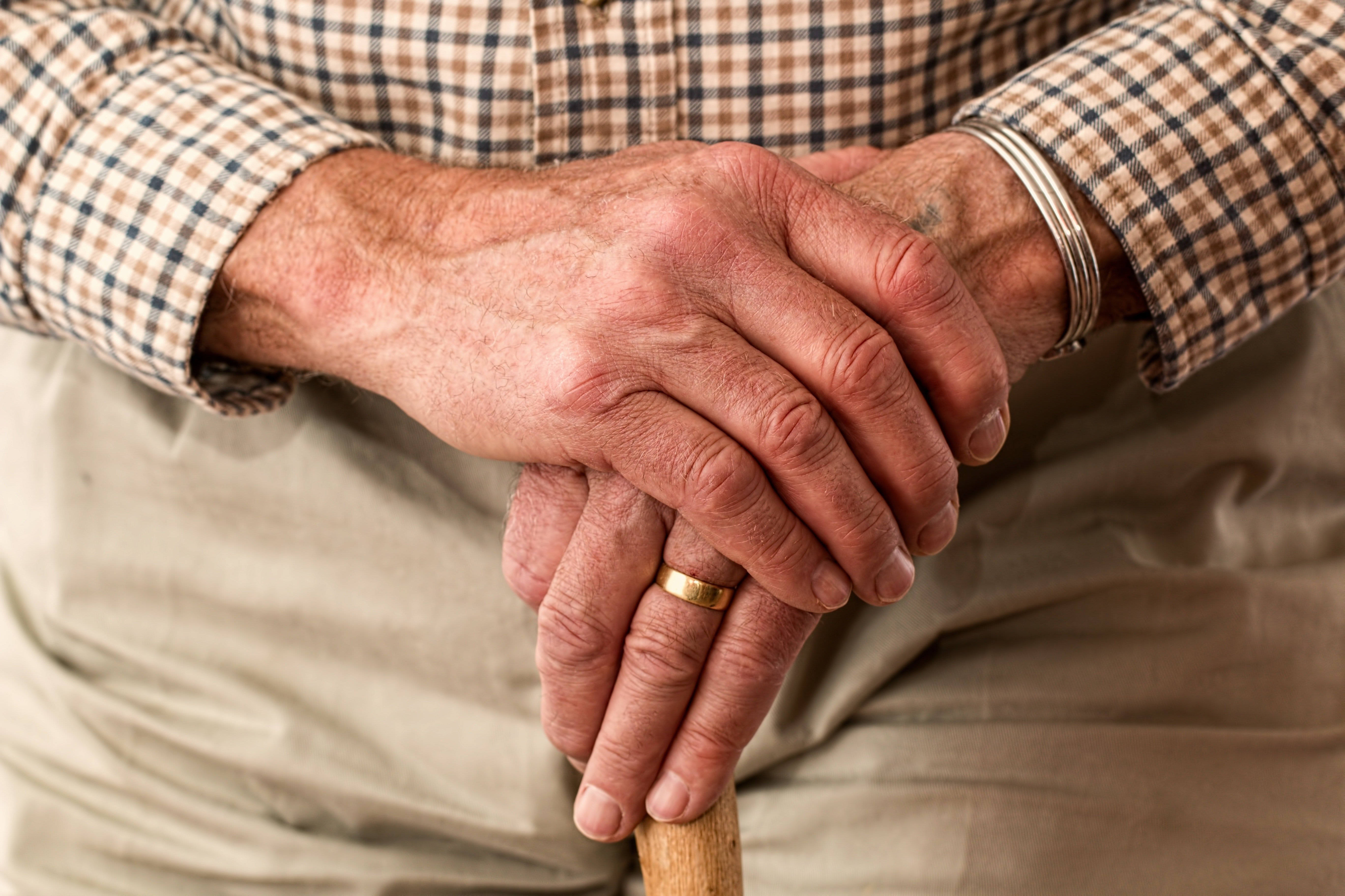 Un anciano sostiene un bastón con sus dos manos. | Foto: Pexels