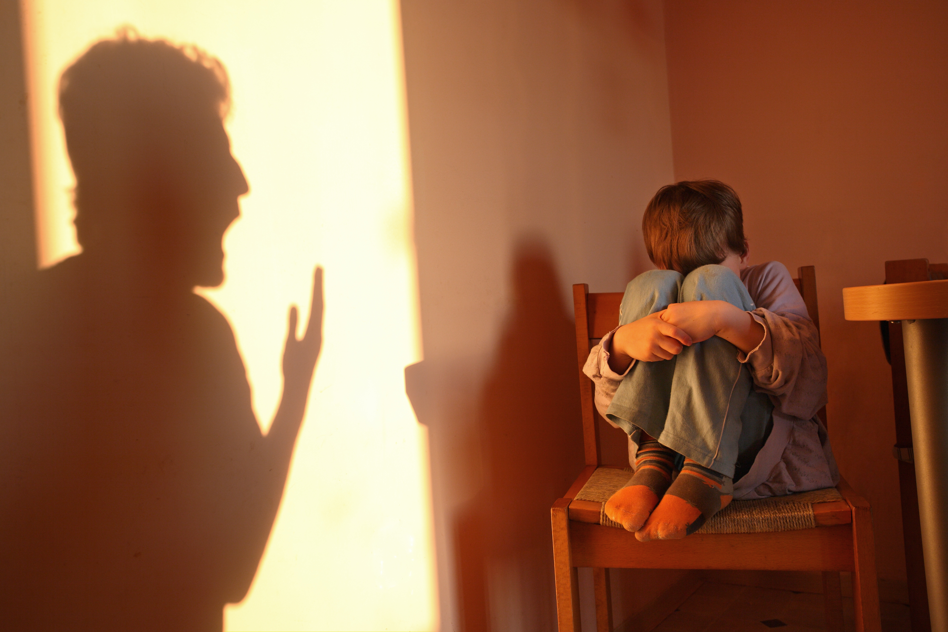 A scared child with the shadow of a man shouting at him | Source: Getty Images