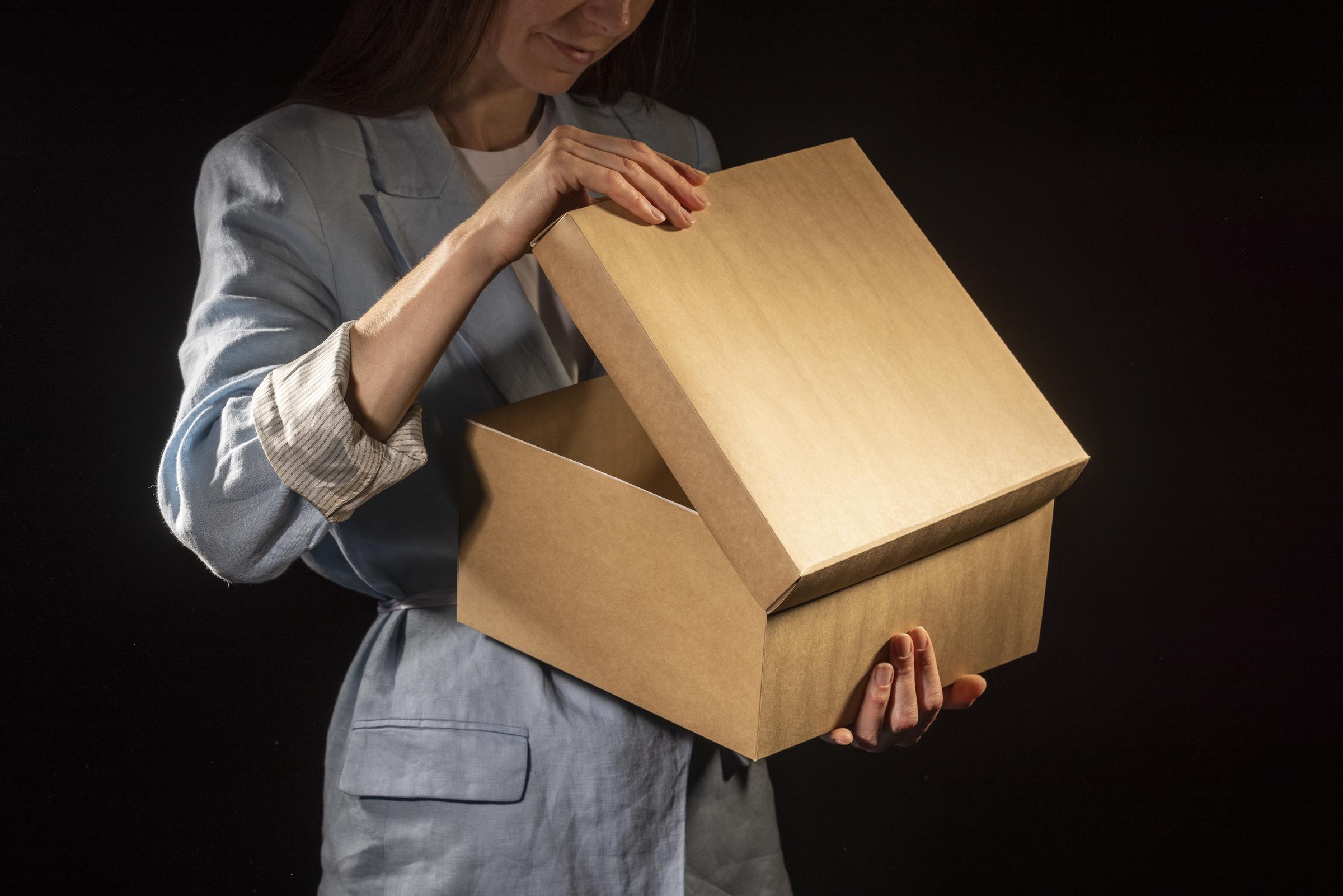 Close-up of a woman looking into a brown box | Source: Freepik