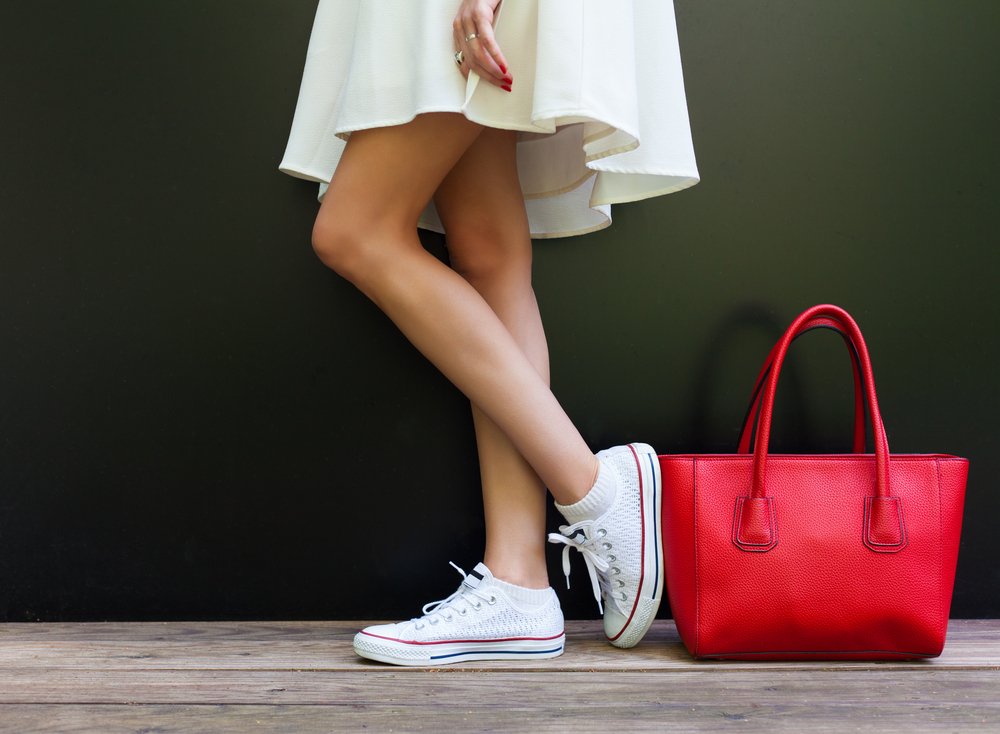 Mujer luciendo zapatillas blancas con una cartera roja. I Foto: Shutterstock.