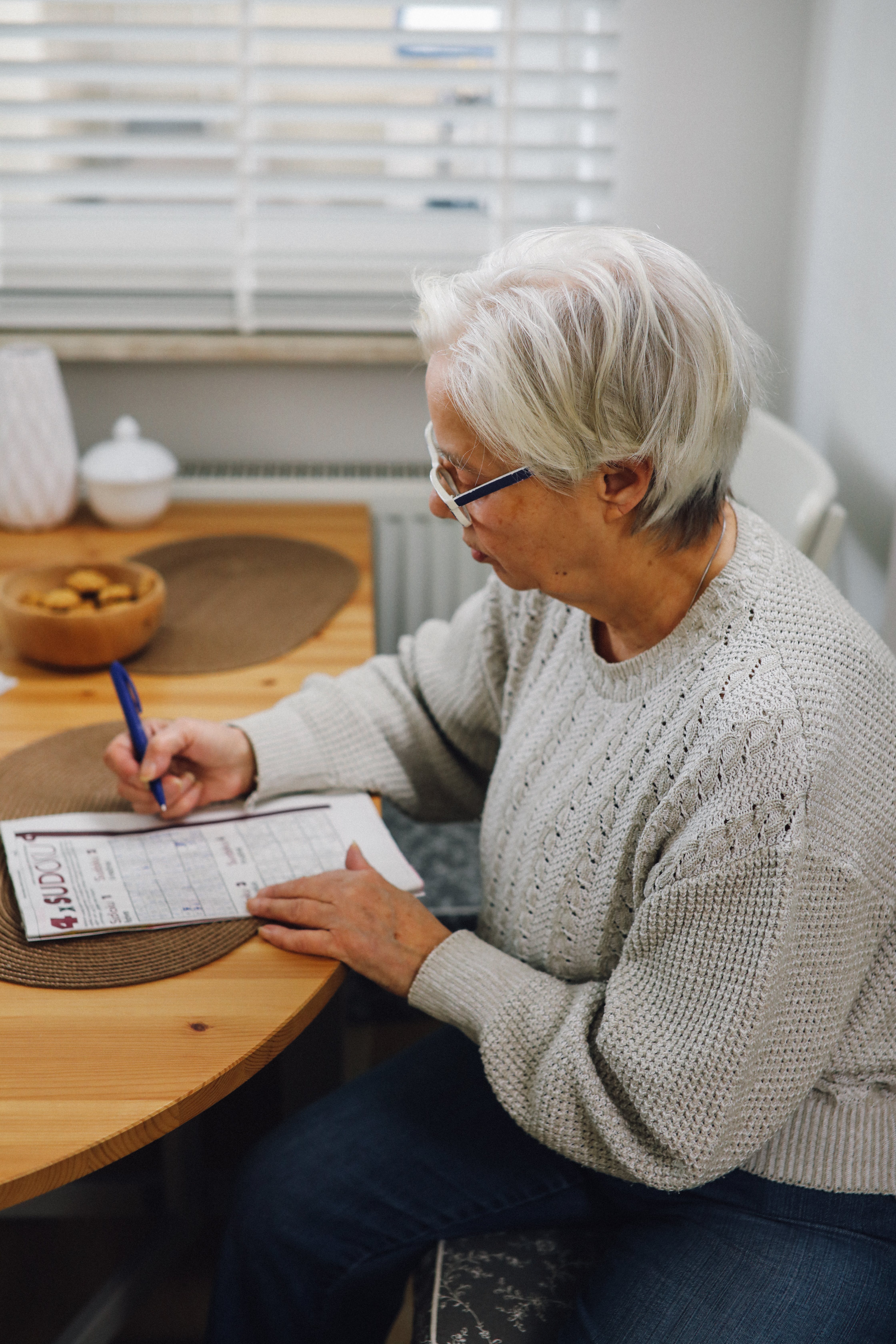 An elderly woman writing on a piece of paper. | Source: Pexels