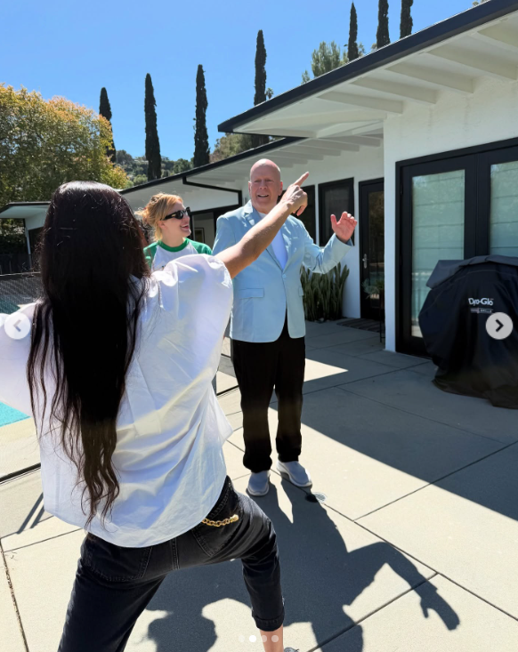 Demi Moore playfully points while Bruce Willis, dressed in a light blue blazer, smiles in the background, posted on March 19, 2025 | Source: Instagram/demimoore