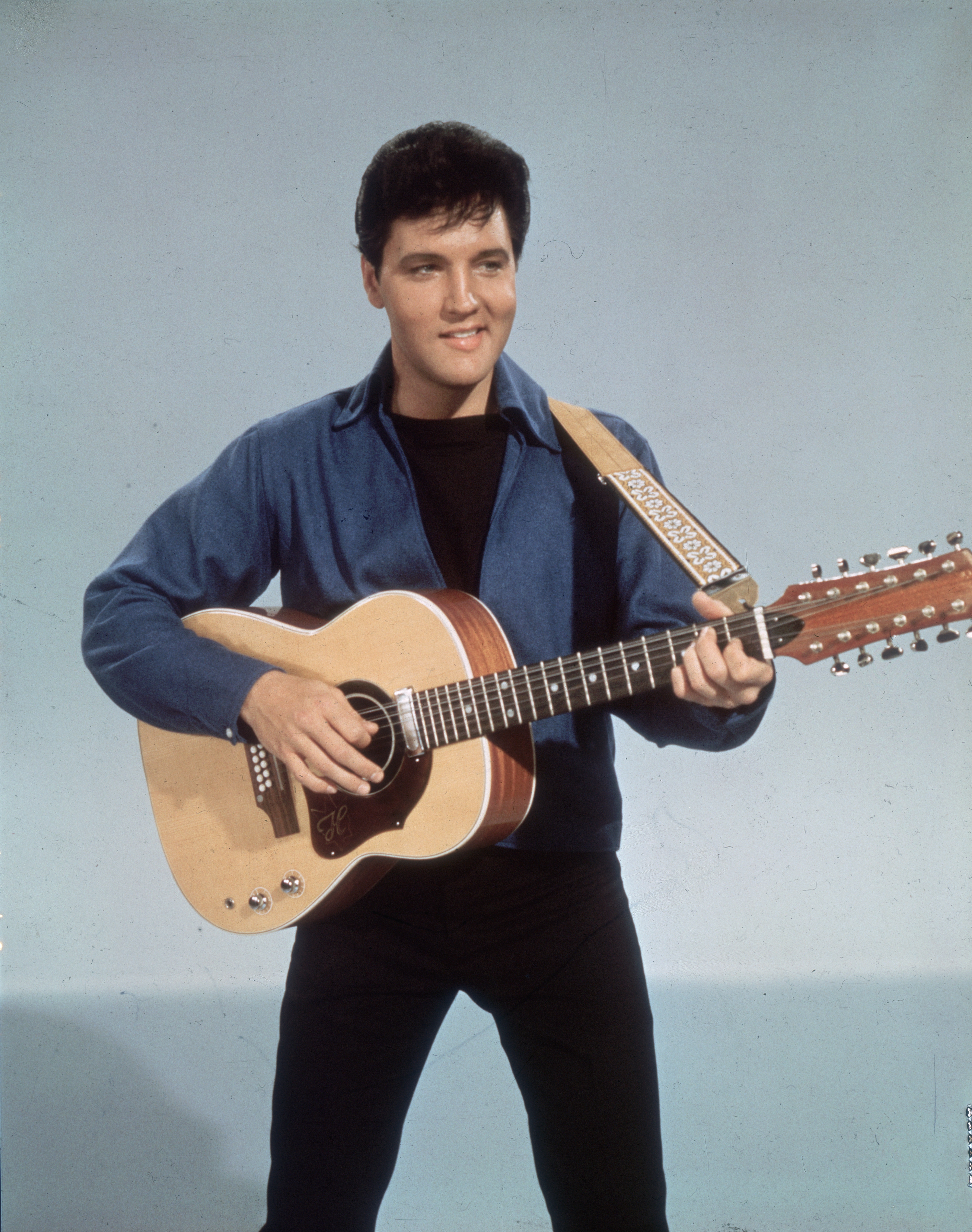 Elvis Presley posing for a picture with a guitar in 1955. | Source: Getty Images