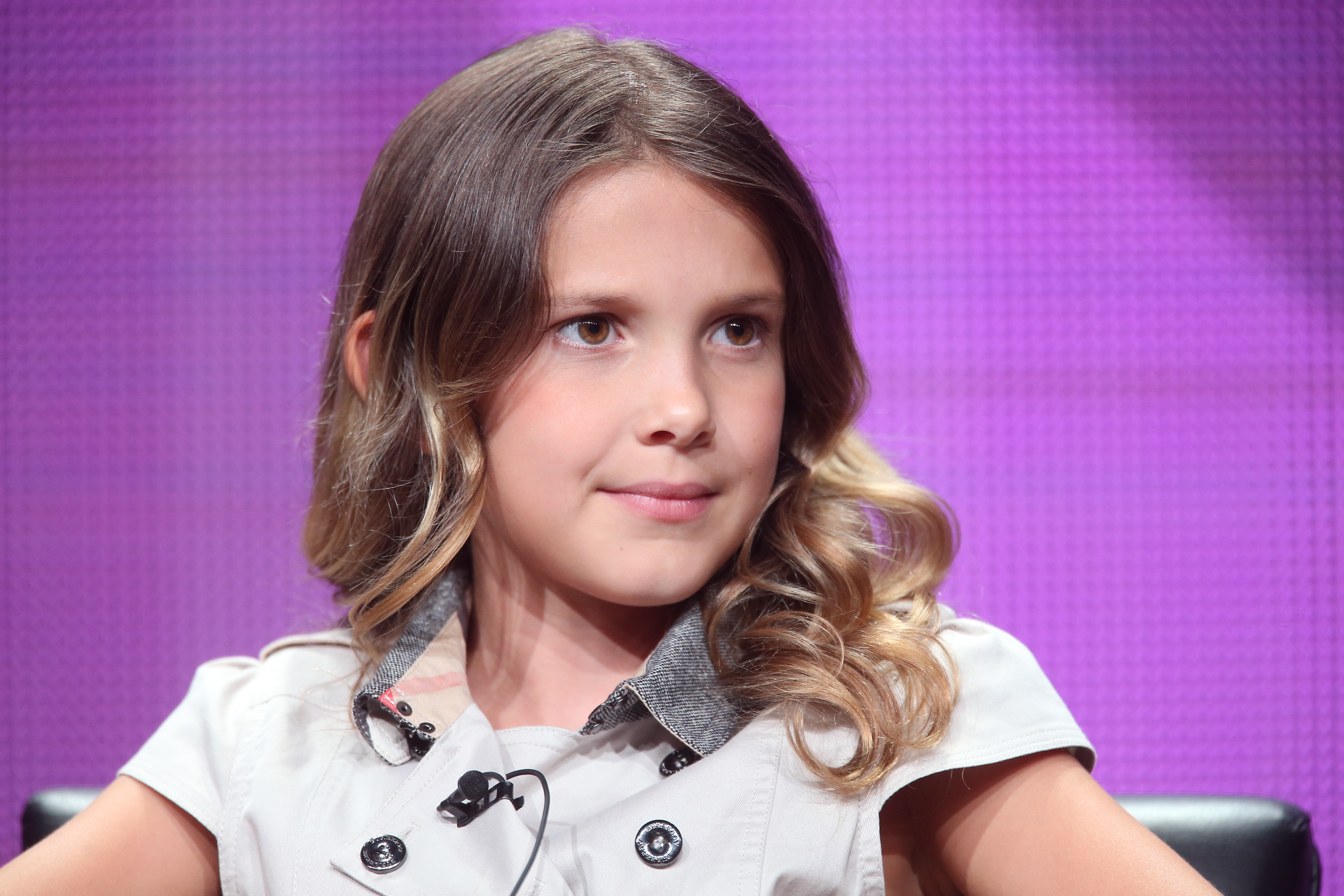 Seated under studio lights, Brown wears her hair longer, cascading softly over her shoulders. The muted tones of her outfit keep the focus on her expressive eyes and calm demeanor. It's a poised, thoughtful look that hints at maturity beyond her years.