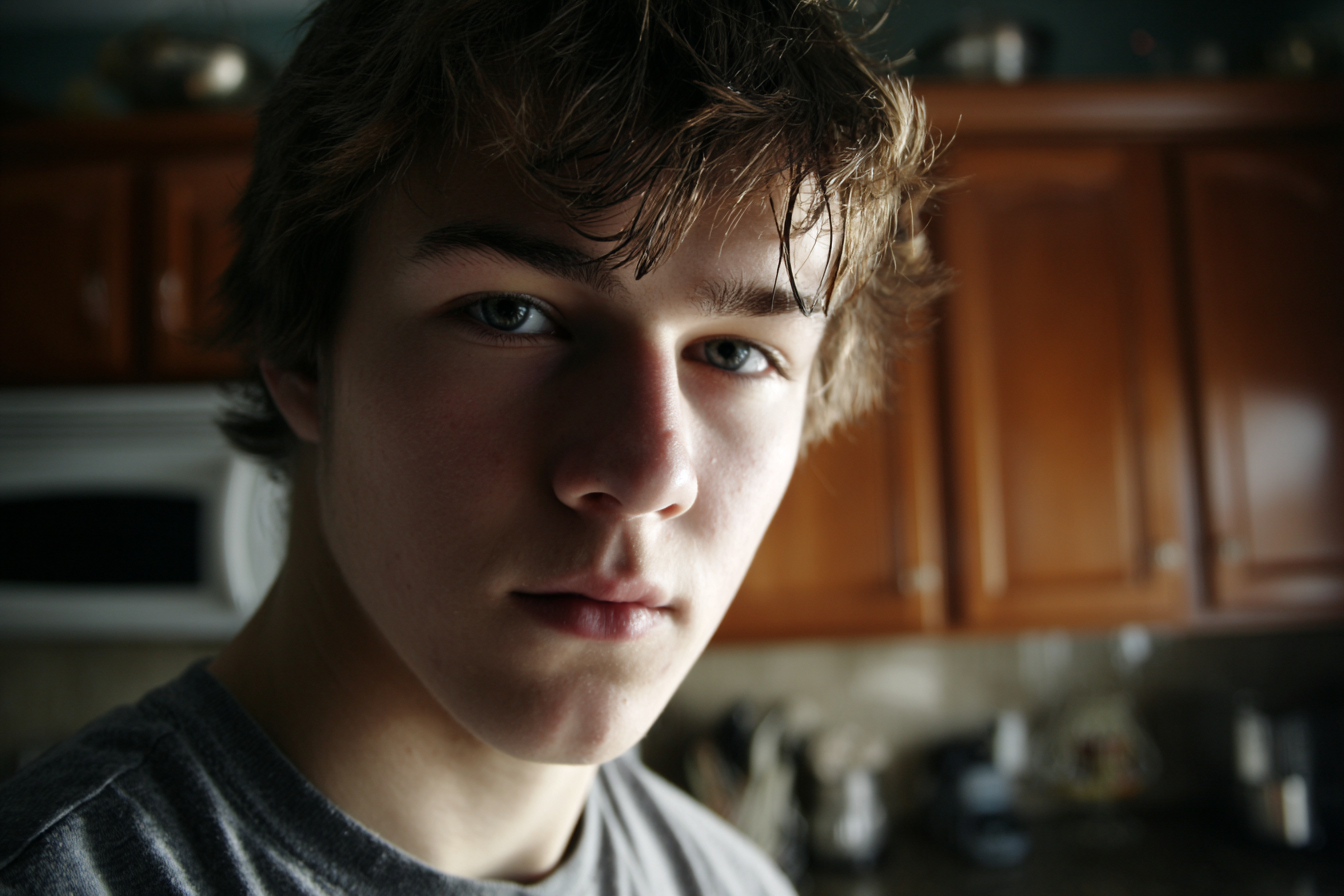 A teenage boy standing in the kitchen and looking at someone | Source: Midjourney