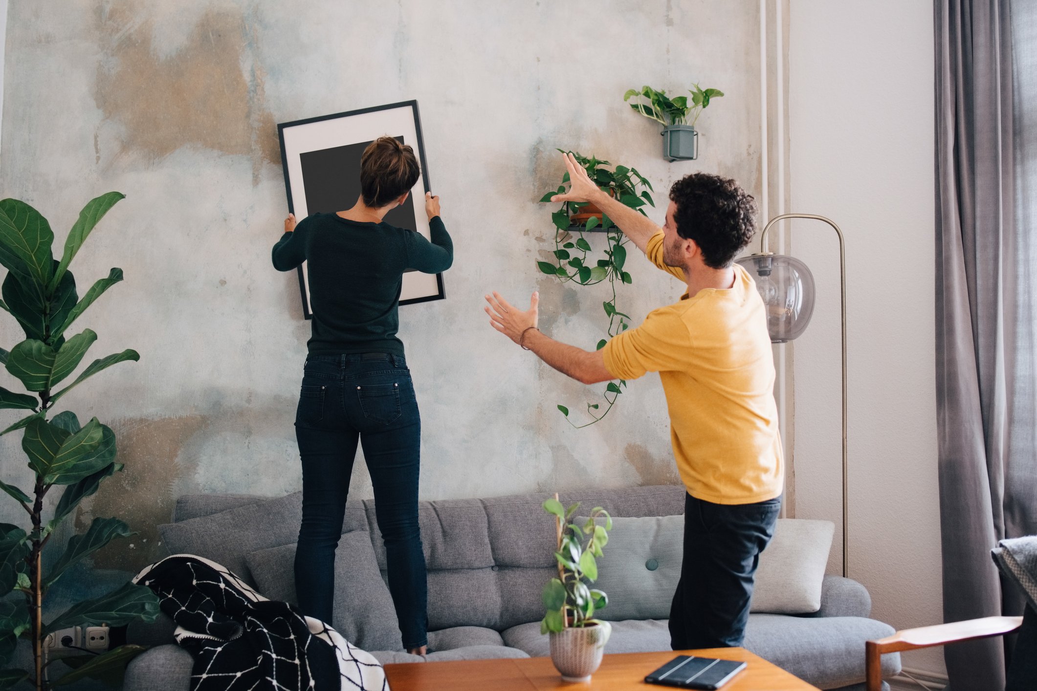 Ein Paar hängt einen Bilderrahmen an die Wand in einem neuen Zuhause. I Quelle: Getty Images