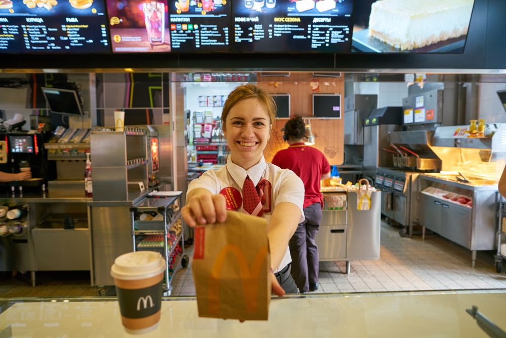 Employee handing over a McDonalds' order to a customer. │Source: Shutterstock