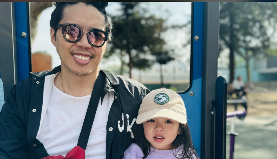 Alex Duong smiles beside his daughter Everest, who sits close in a cap, the two sharing a relaxed, sunlit moment together. | Source: GoFundMe