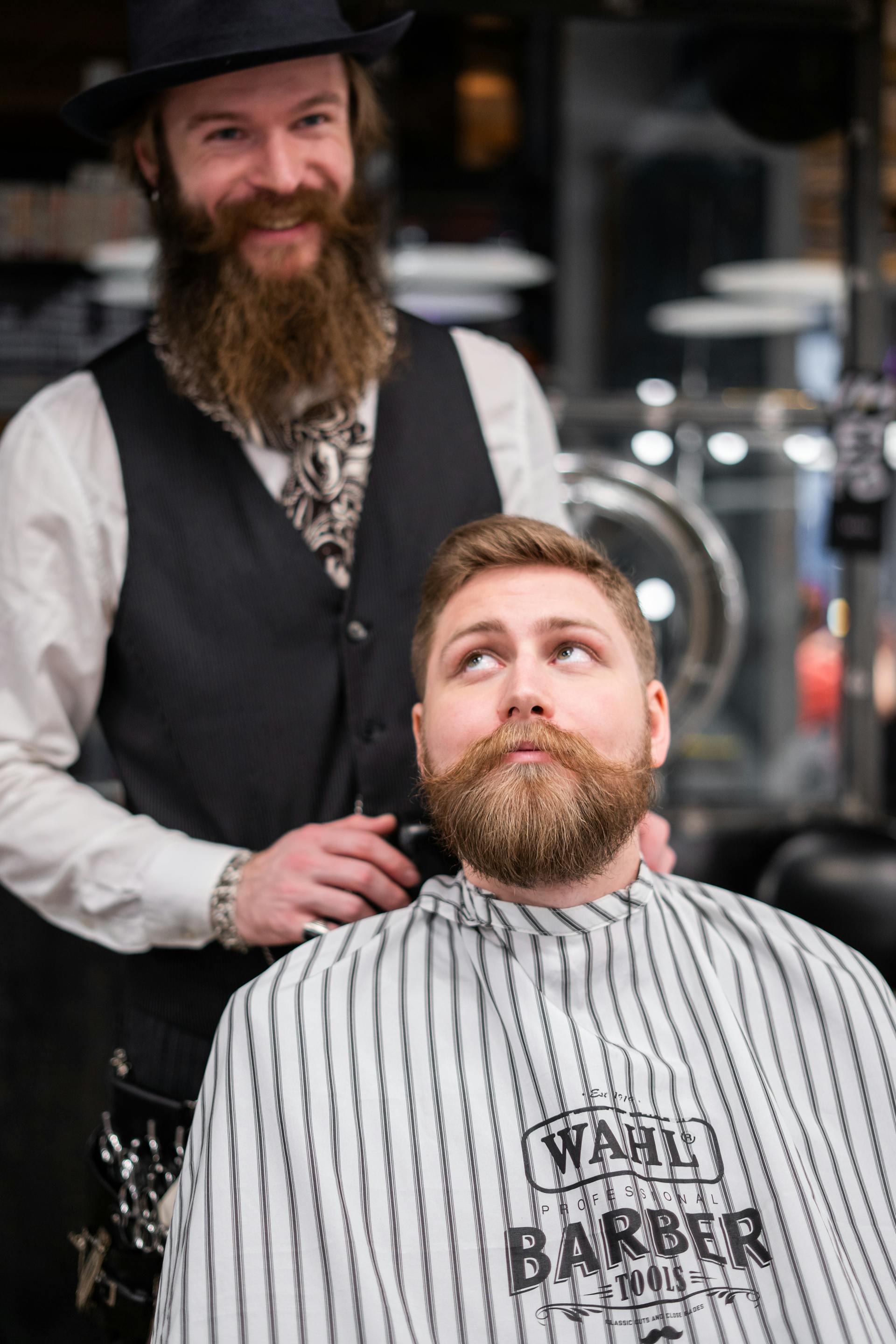 A barber smiles while standing behind a customer in his shop | Source: Pexels