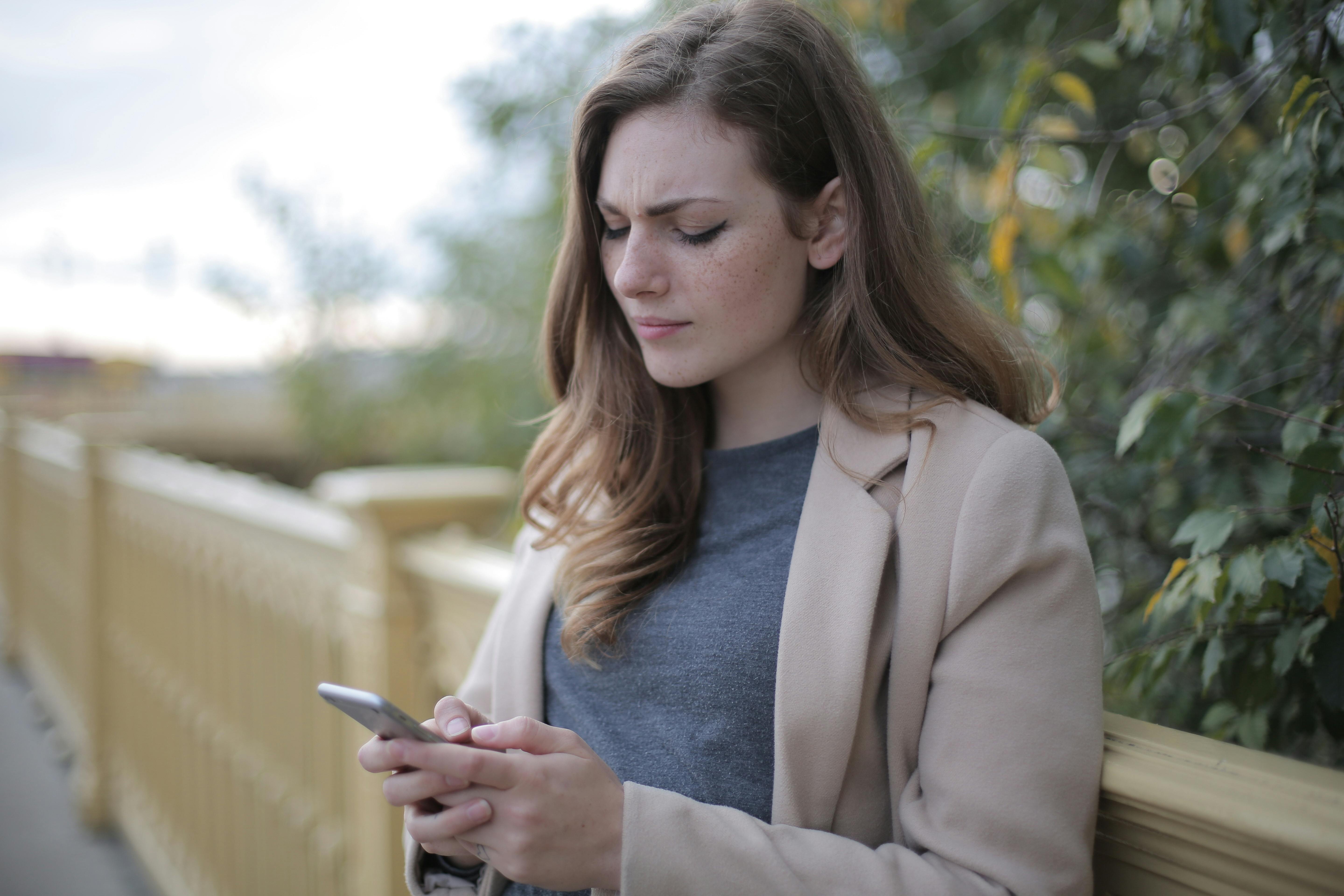 An unhappy woman reading something on her phone | Source: Pexels