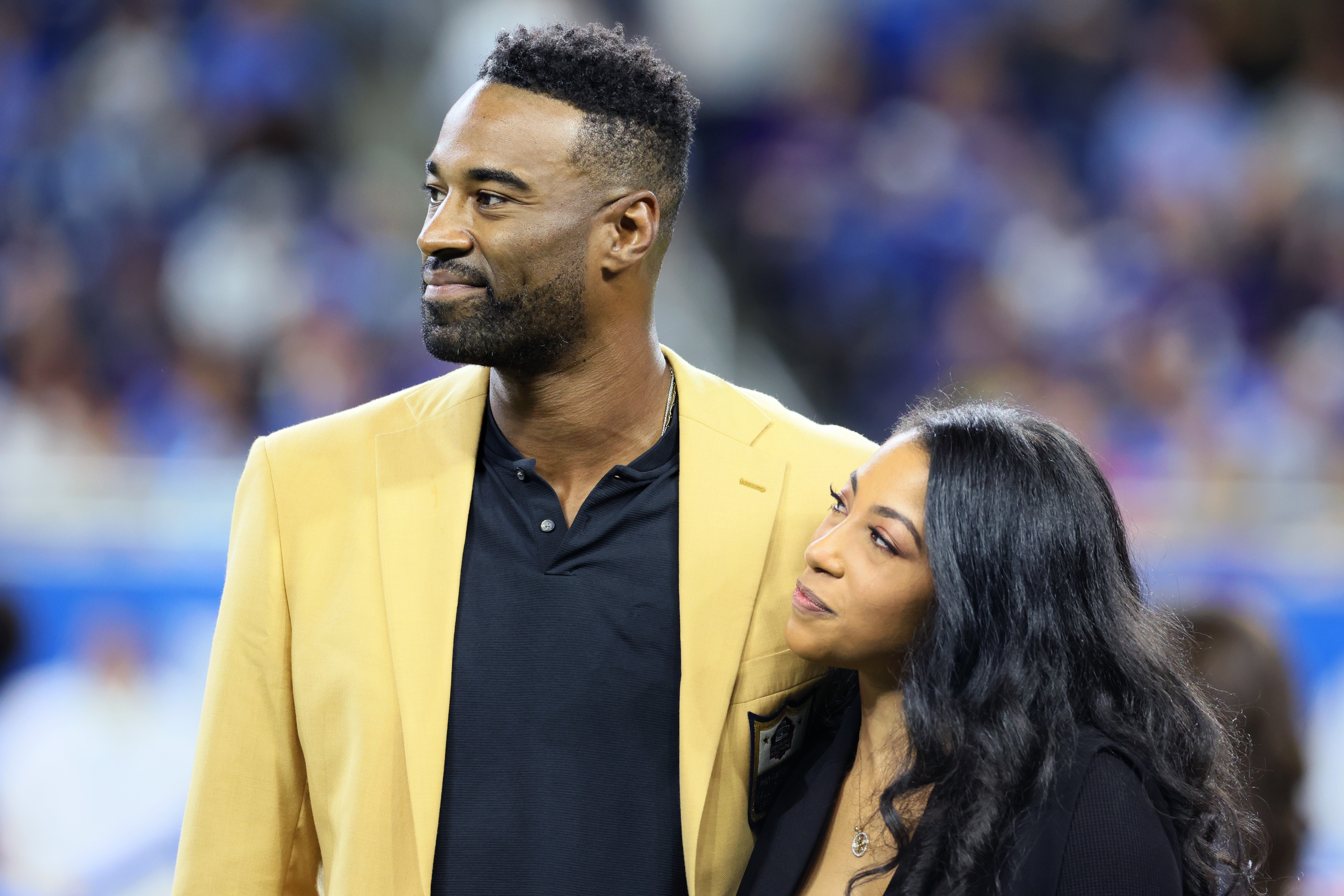 Calvin Johnson, Jr. stands with Brittney McNorton, as he is honored after his induction into the Hall of Fame in a special ceremony during halftime of an NFL football game between the Detroit Lions and the Baltimore Ravens on September 26, 2021, in Detroit, Michigan. | Source: Getty Images