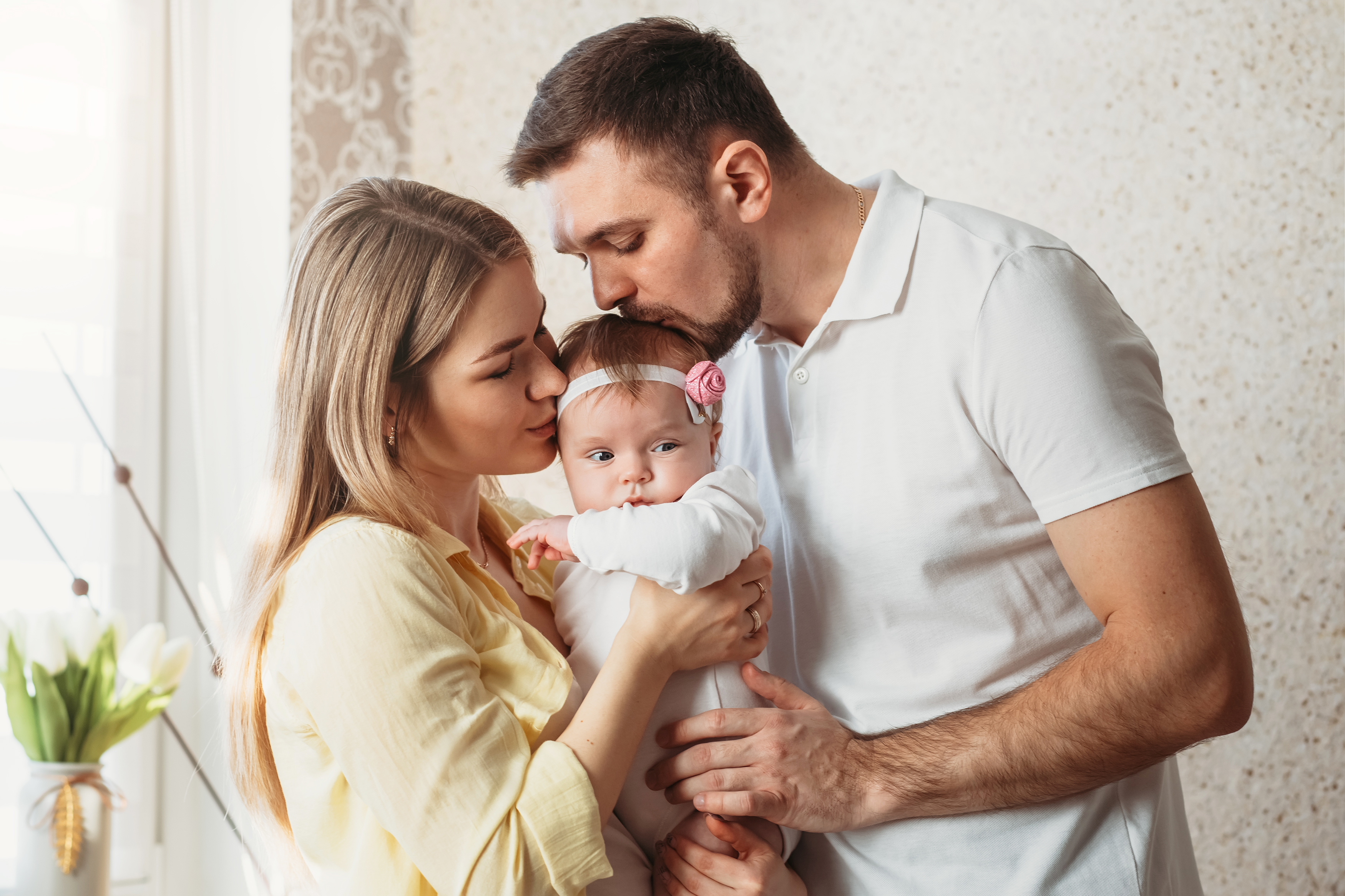 New parents kissing their baby girl | Source: Shutterstock