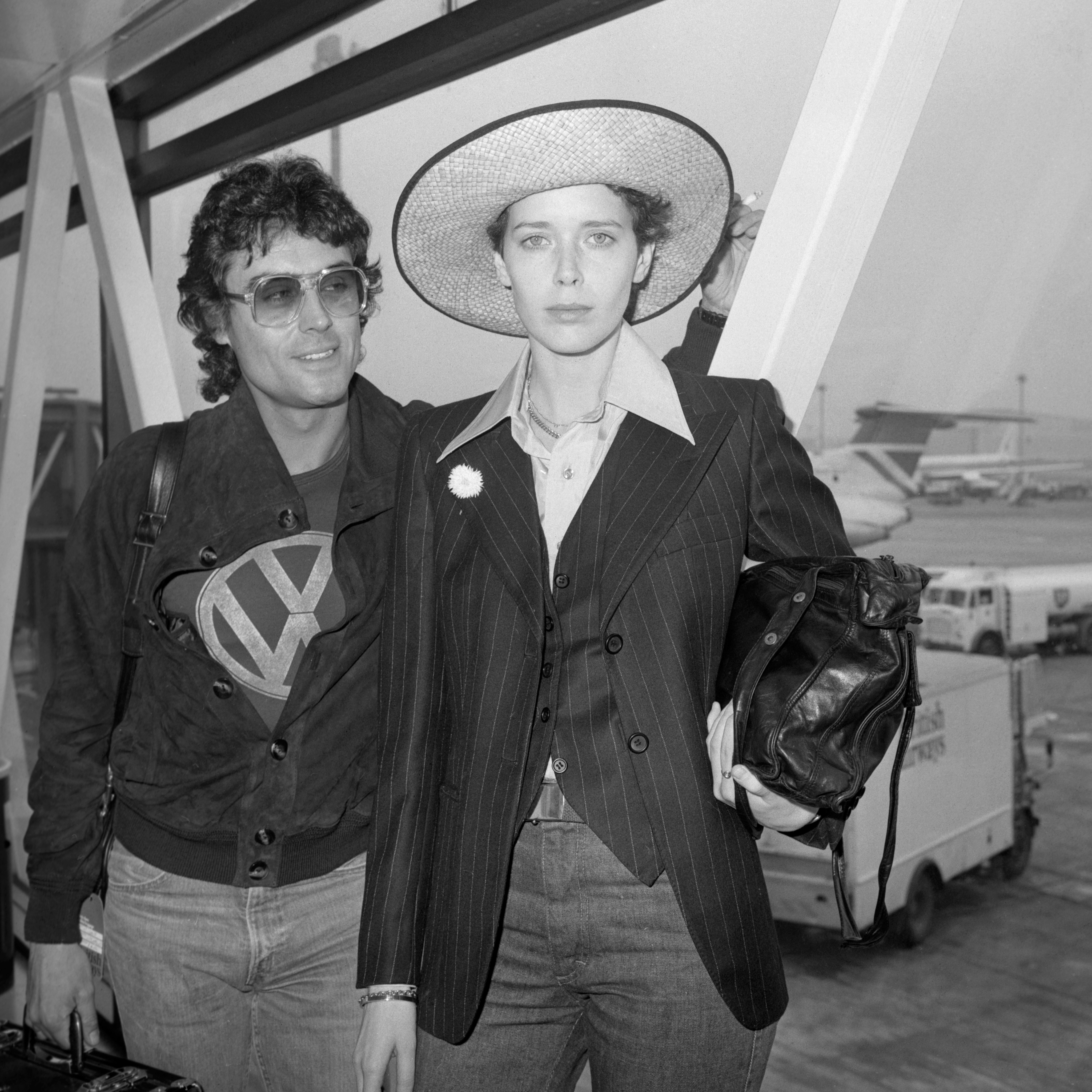 Ian McShane and his Dutch actress and model girlfriend Sylvia Kristel pose at London Heathrow Airport on June 13, 1977 in London | Source: Getty Images