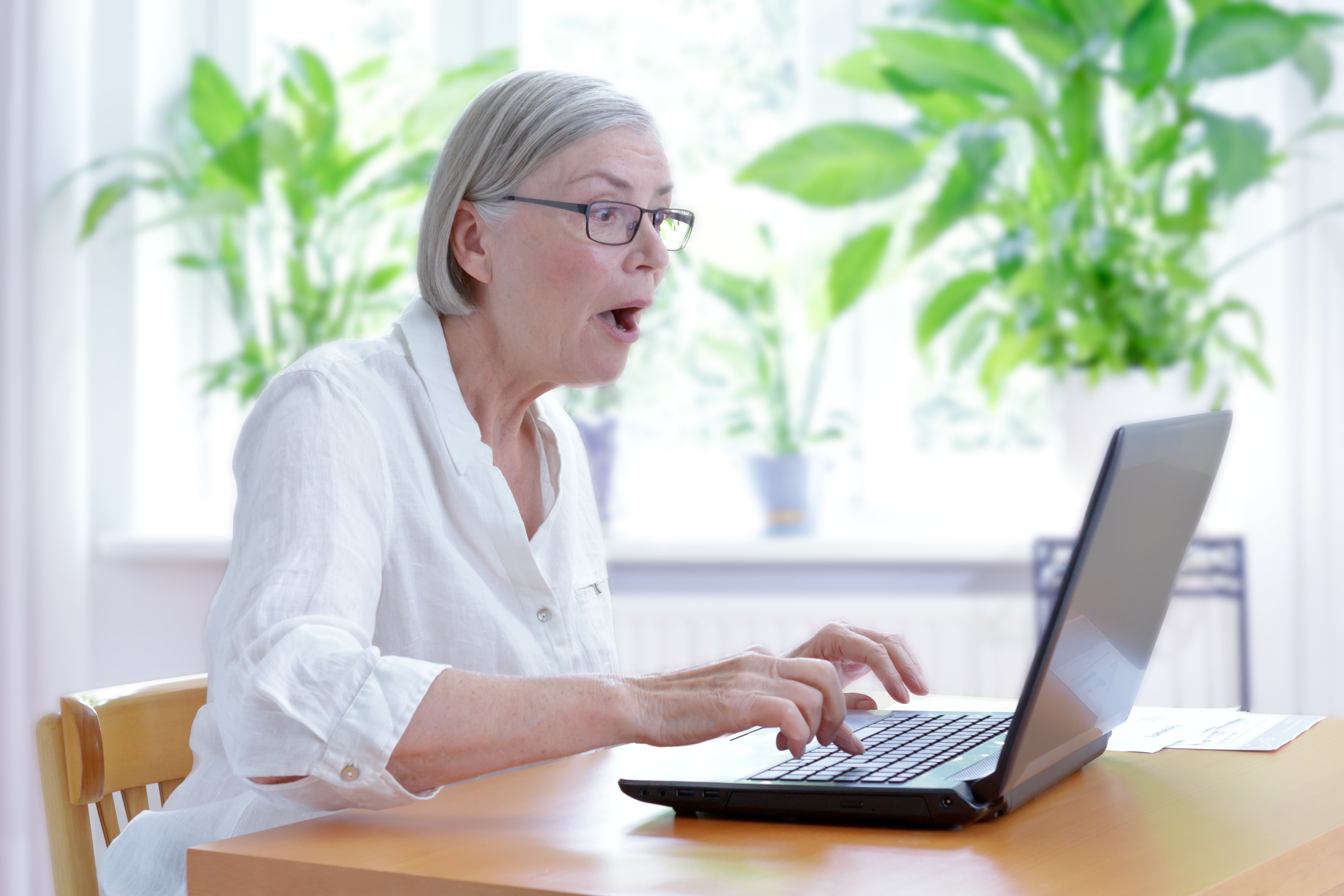 Elderly woman shocked while staring at laptop screen. | Source: Shutterstock