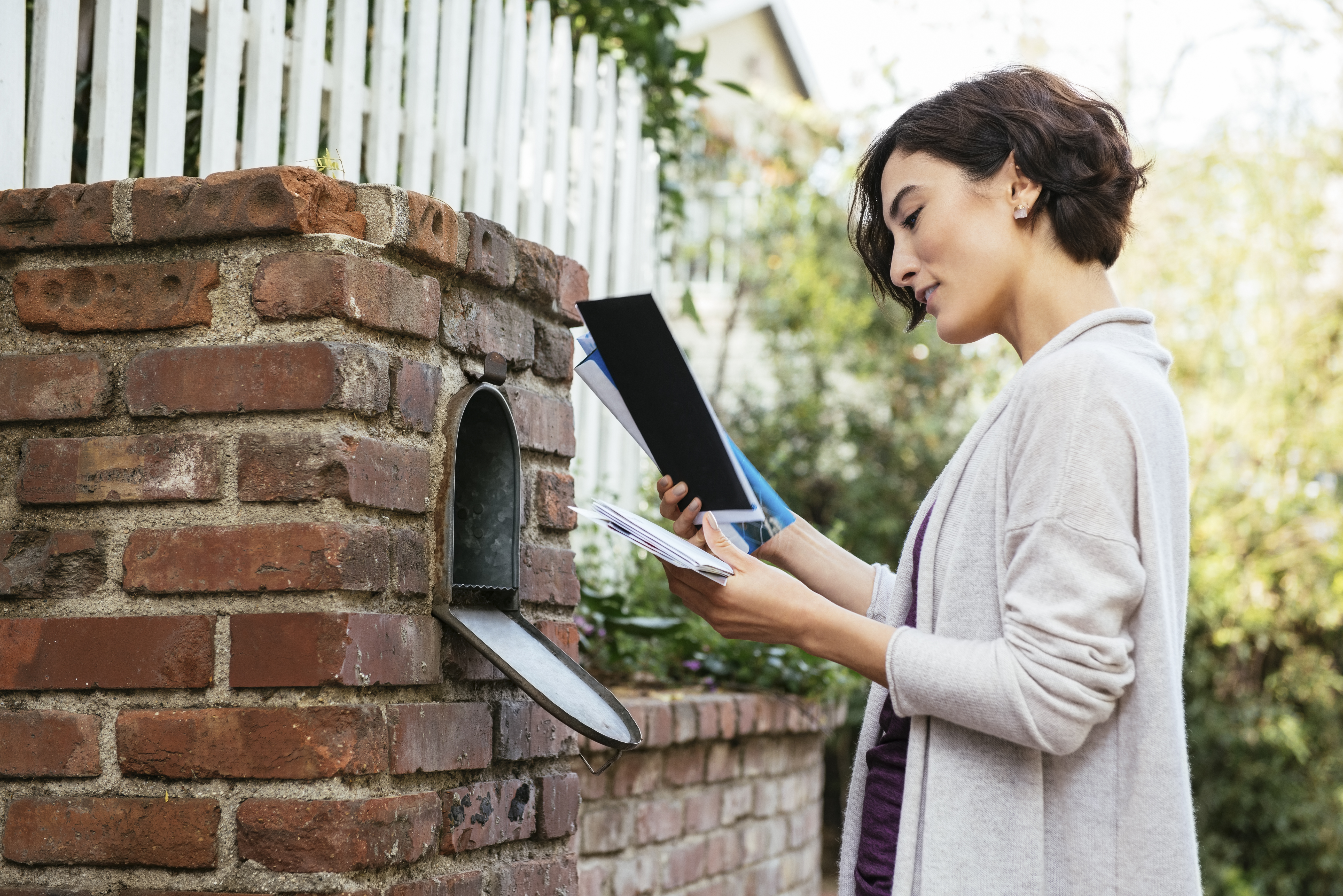 Side view of beautiful young woman at mailbox | Source: Getty Images