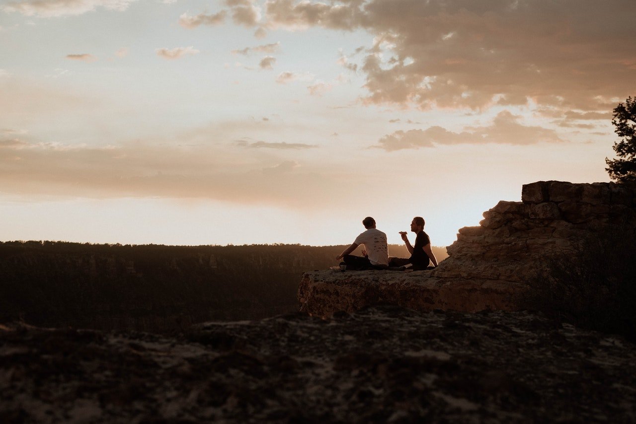 Two men sitting on a rock | Pexels