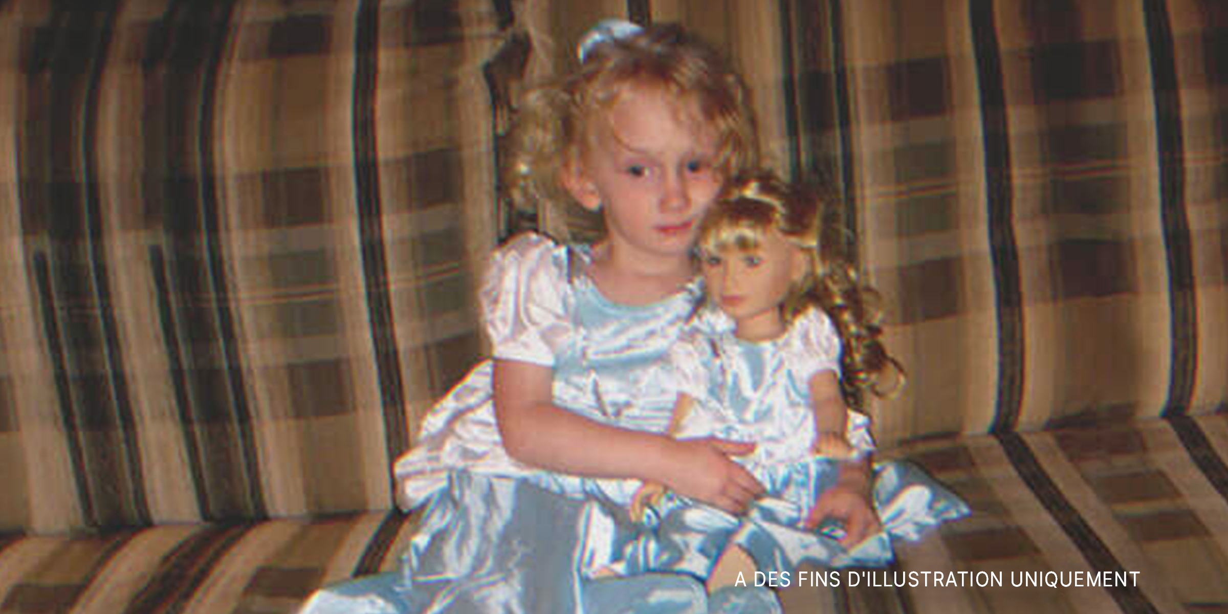 Un petite fille tenant une poupée sur un canapé. | Source : Flickr / Elizabeth/Table4Five (CC BY 2.0)