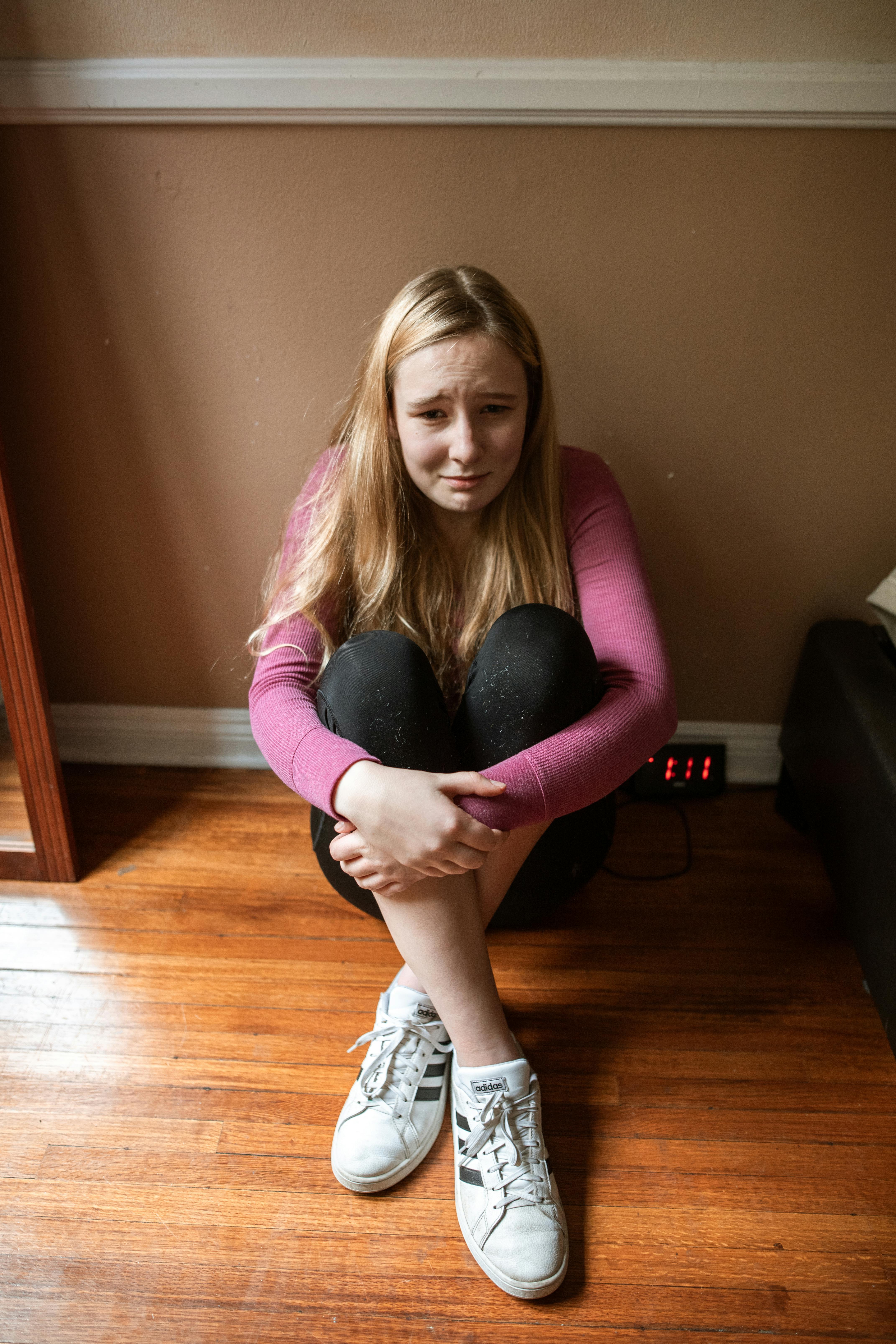A teenage girl sitting on the floor crying | Source: Pexels