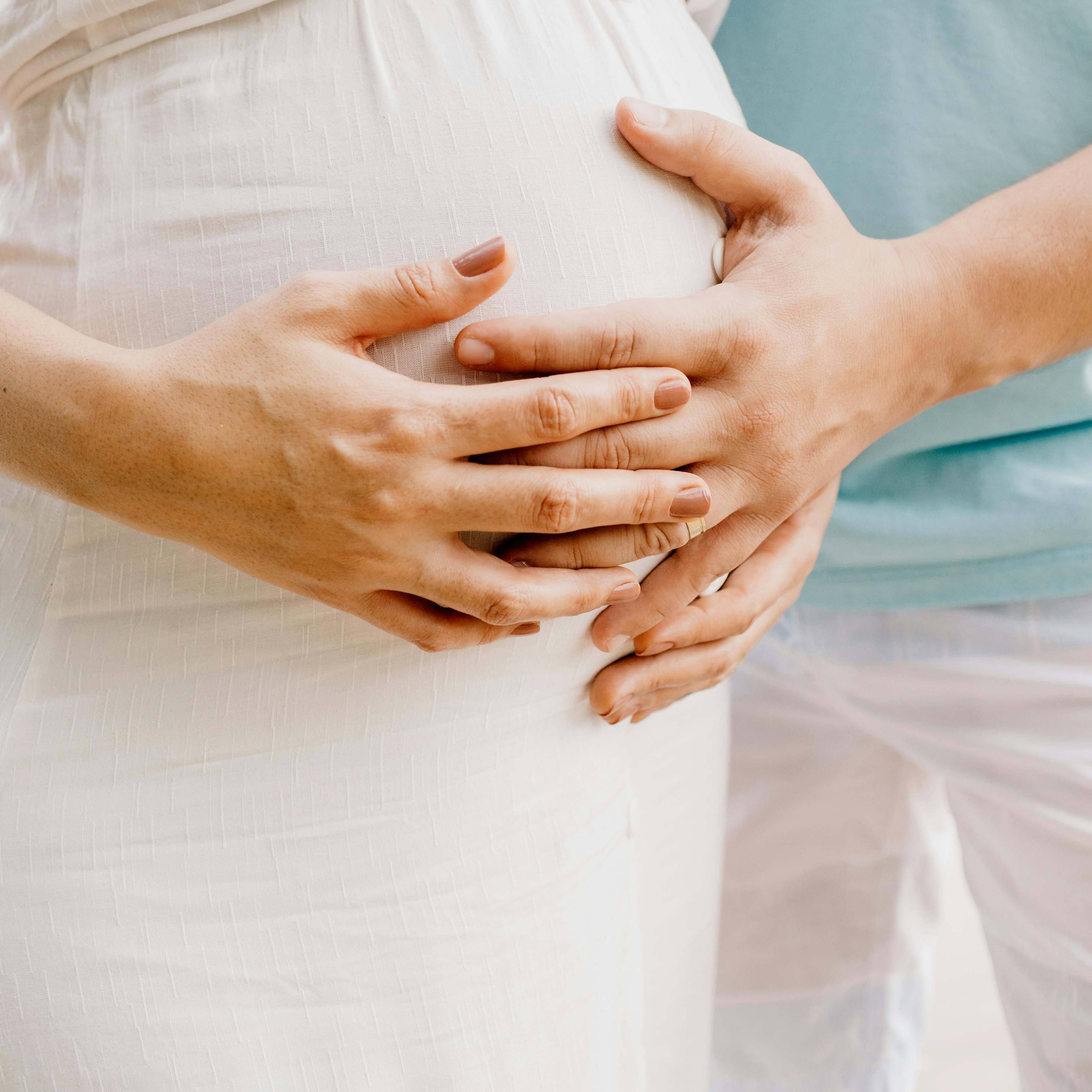 A pregnant woman pictured with a man's hand on her belly | Source: Pexels