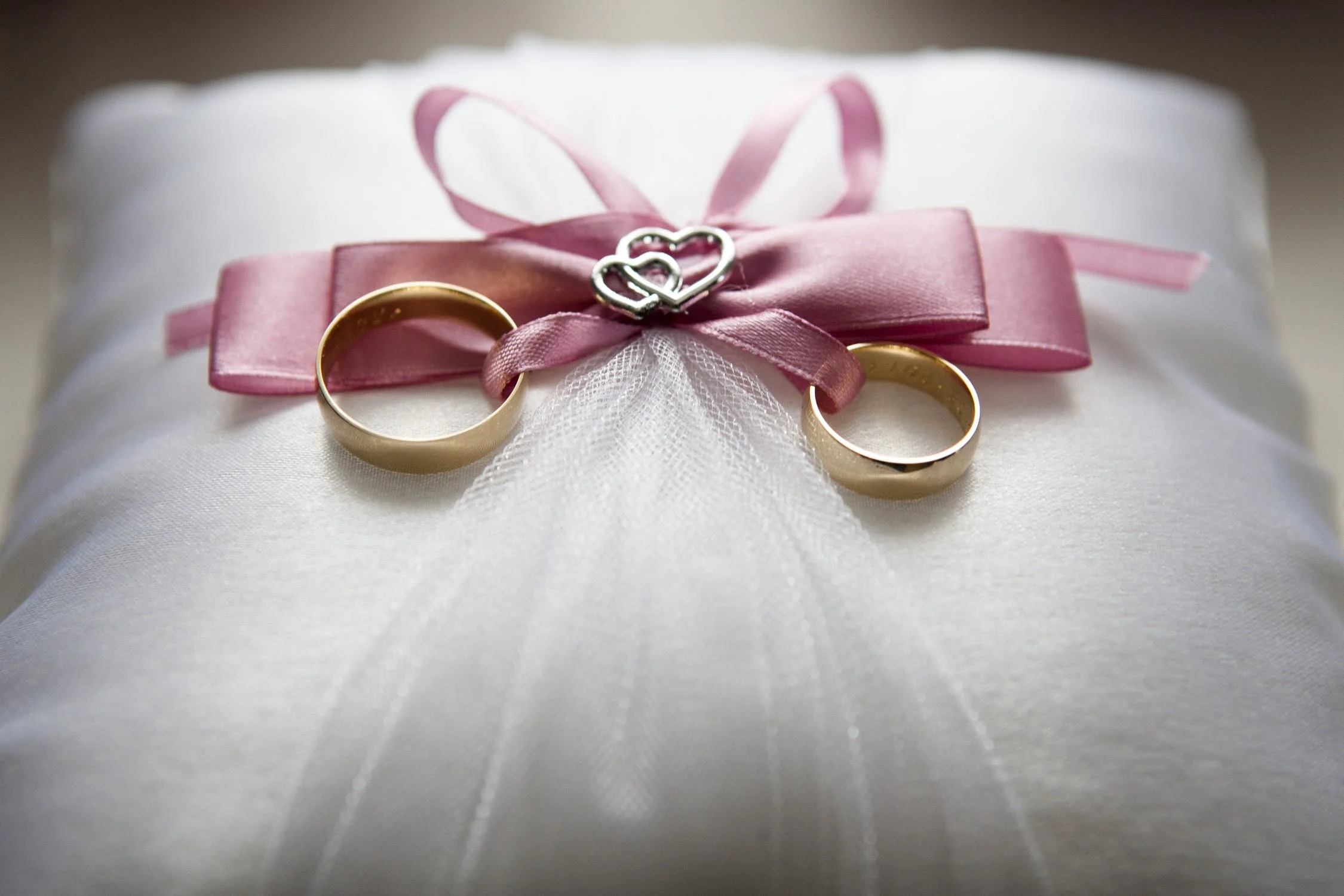 A pair of wedding rings placed on a pink bow. | Source: Pexels