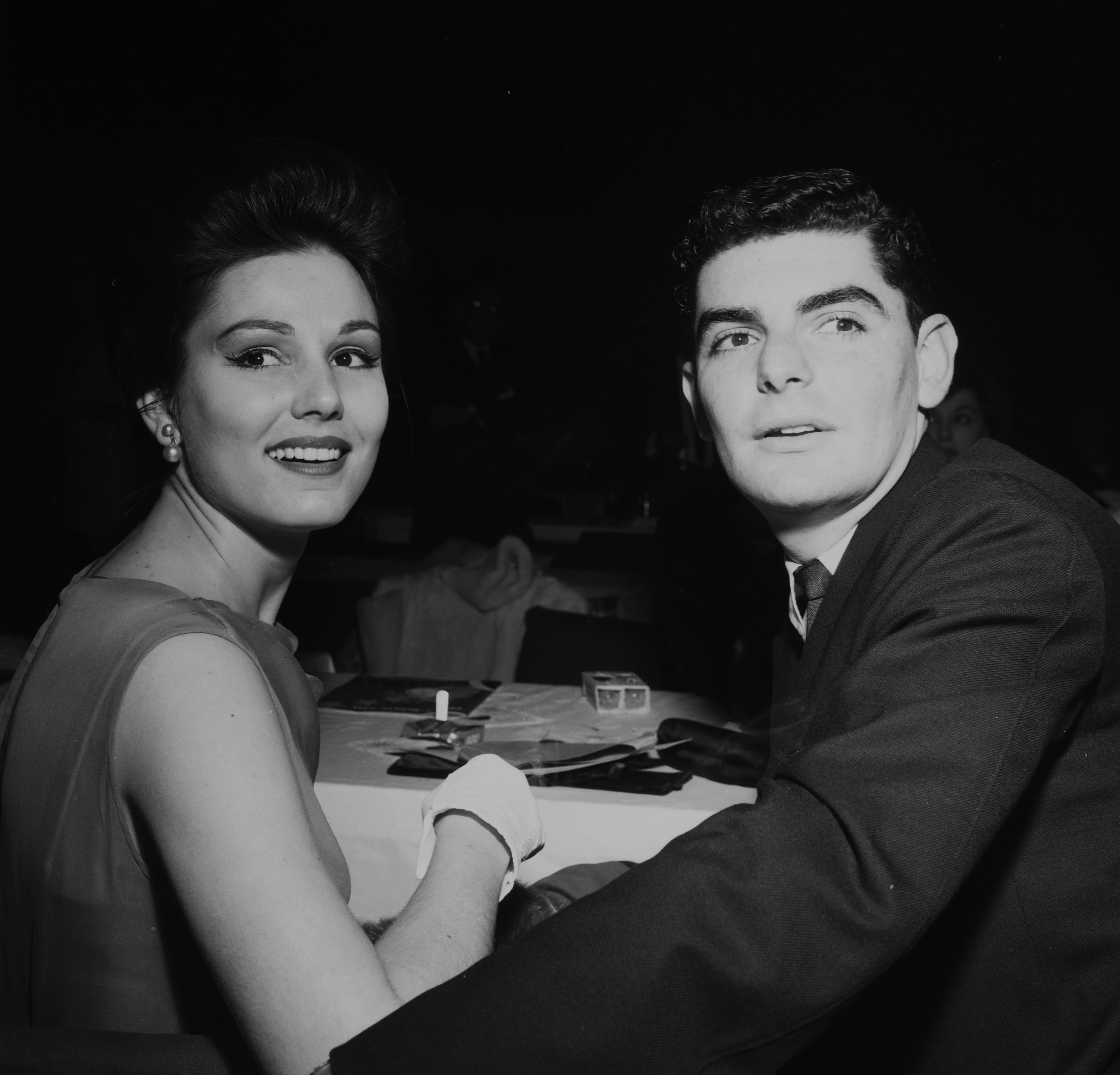 A young Richard Benjamin and Paula Prentiss are seen seated closely together at a formal dinner in Los Angeles, circa 1961. Elegantly dressed, the couple shares a poised moment during the evening's festivities, capturing an early glimpse of a partnership that would come to define both their personal lives and Hollywood careers.