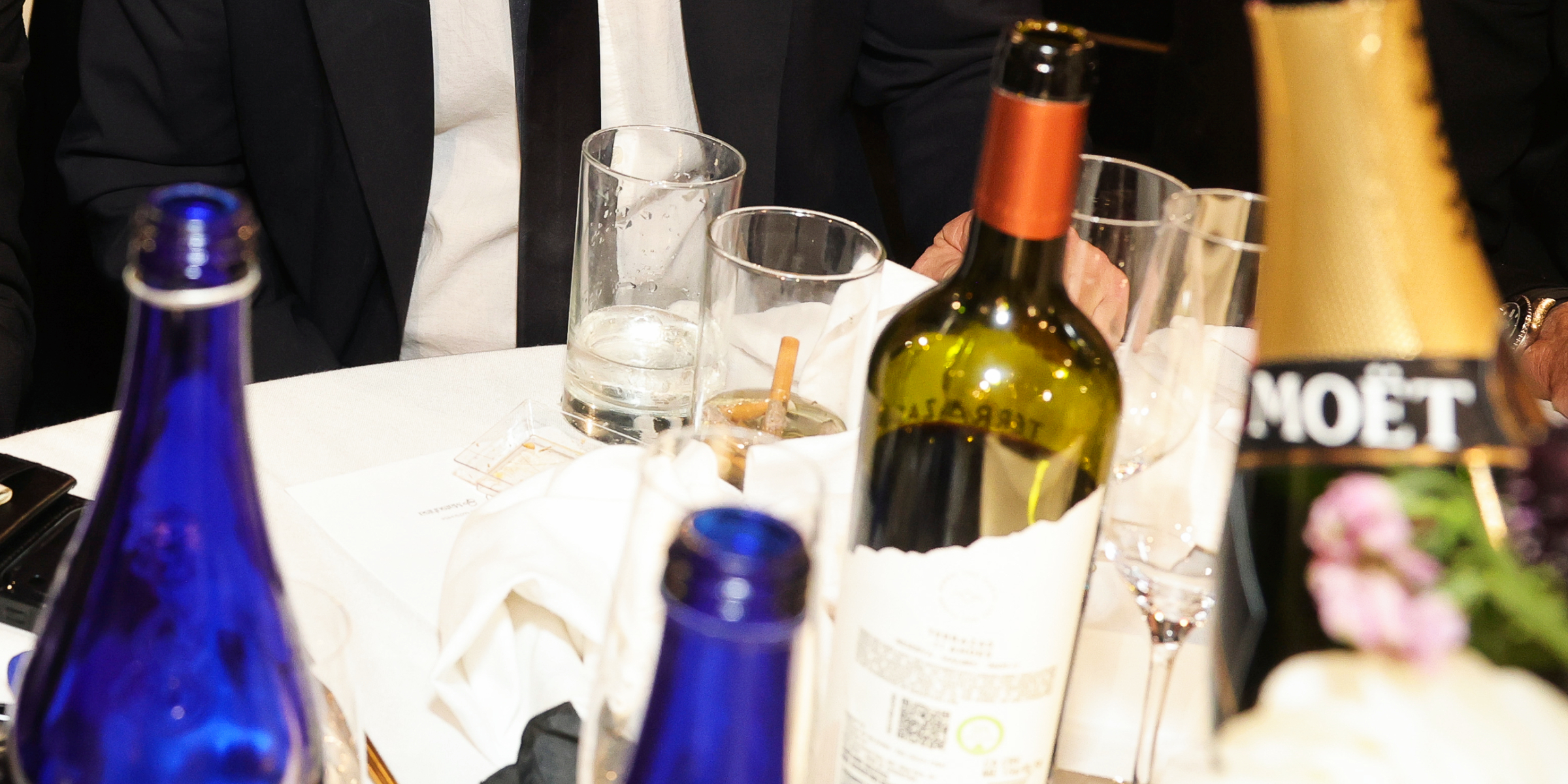A cigarette butt is seen inside a drinking glass at the 2026 Golden Globe Awards, surrounded by bottles and glassware | Source: Getty Images