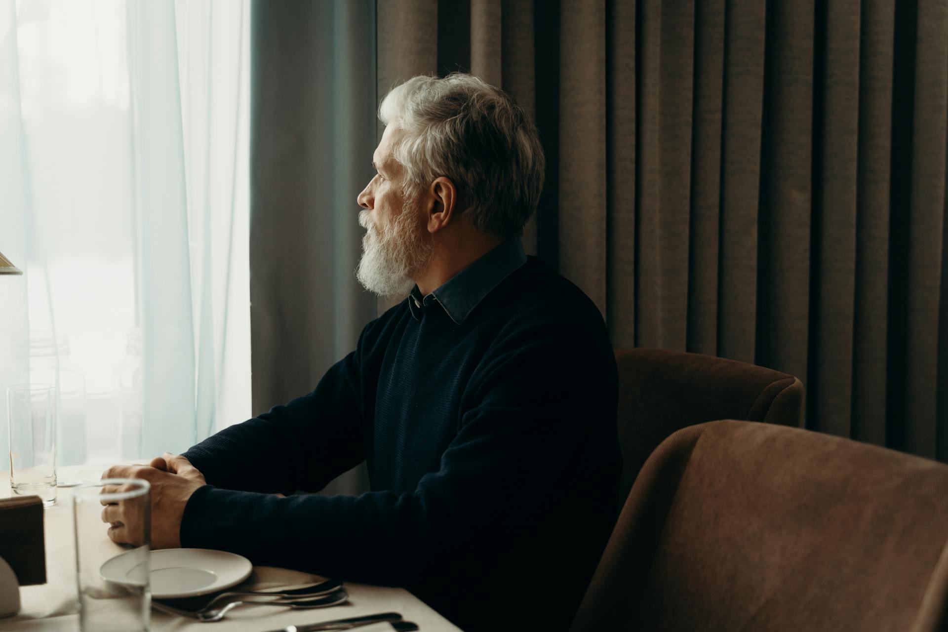 An older man looking outside a window while talking | Source: Pexels