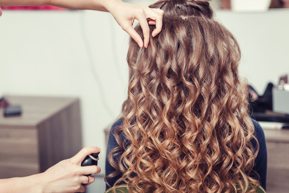 Une femme se faisant poser du produit dans les cheveux. l Source : Shutterstock