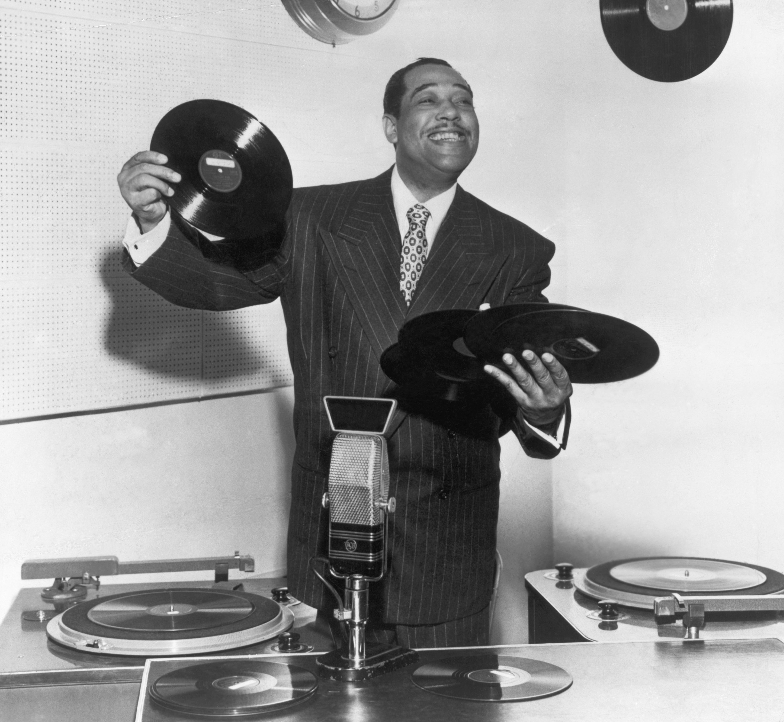 Duke Ellington (1889-1974), bandleader, composer and arranger, has his hands full as he tries role of disc jockey | Photo: Getty Images