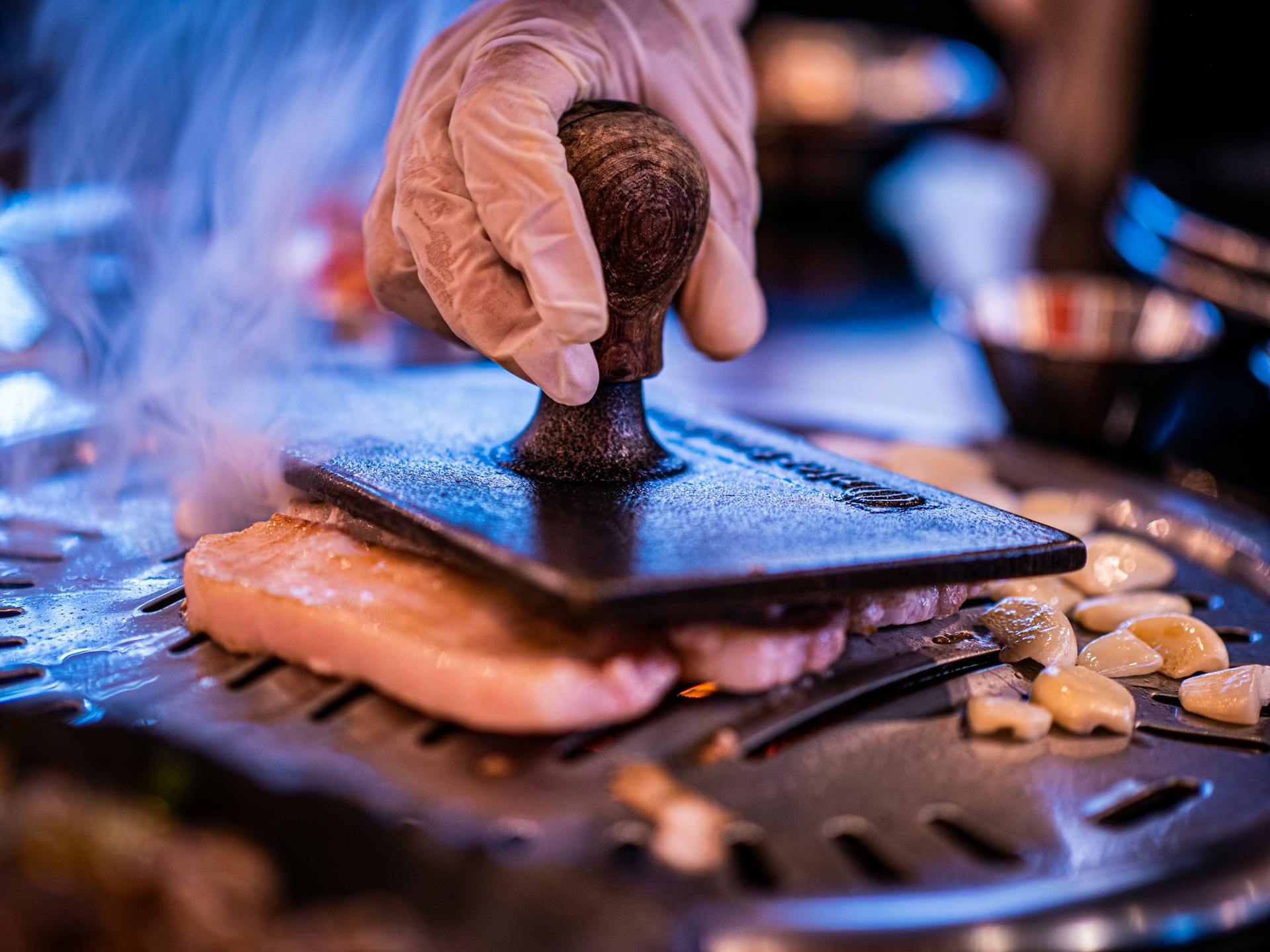 A person wearing a glove grilling meat | Source: Pexels